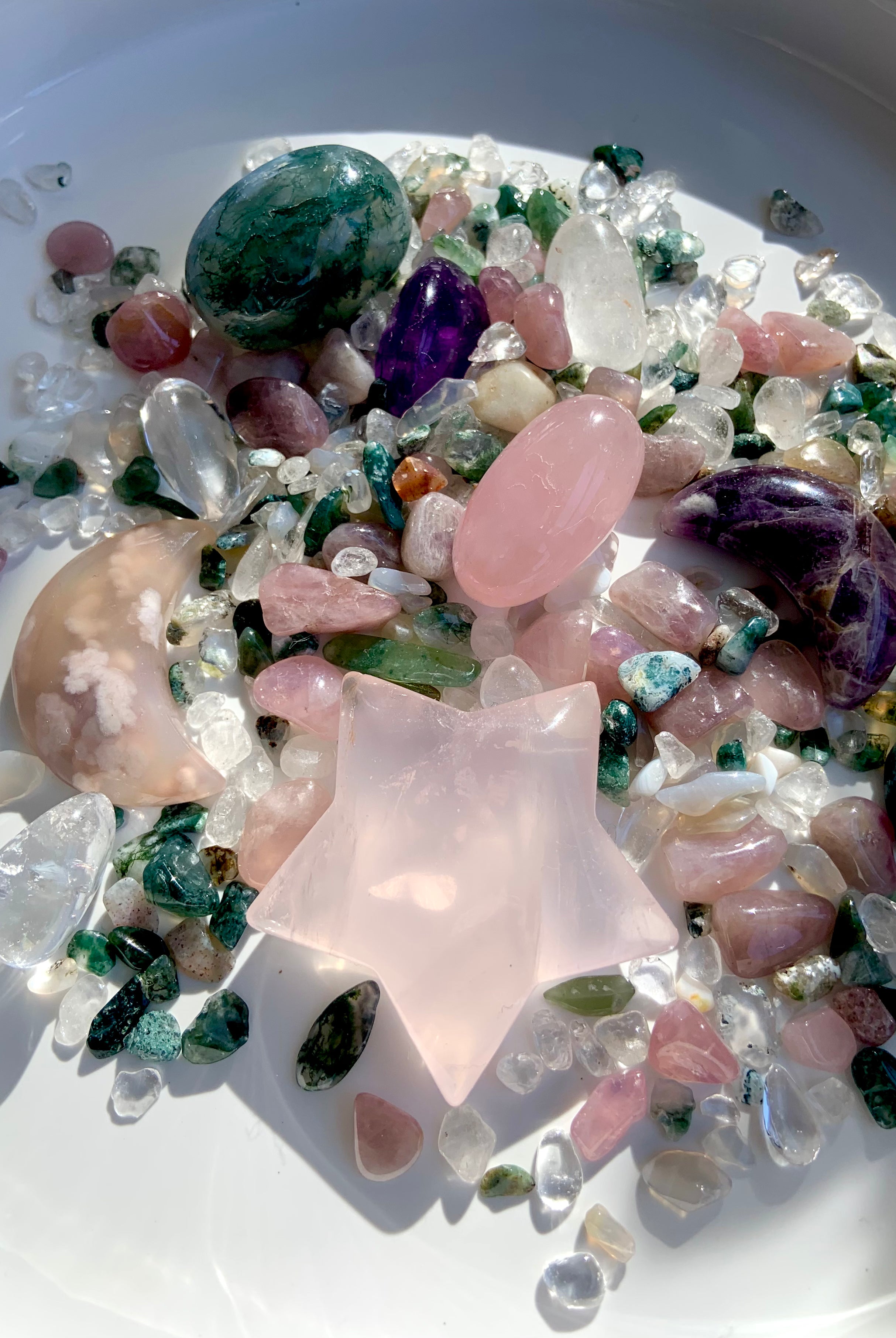 large rose quartz star carving displayed in a bowl of mixed healing crystals for heart chakra décor and gifting