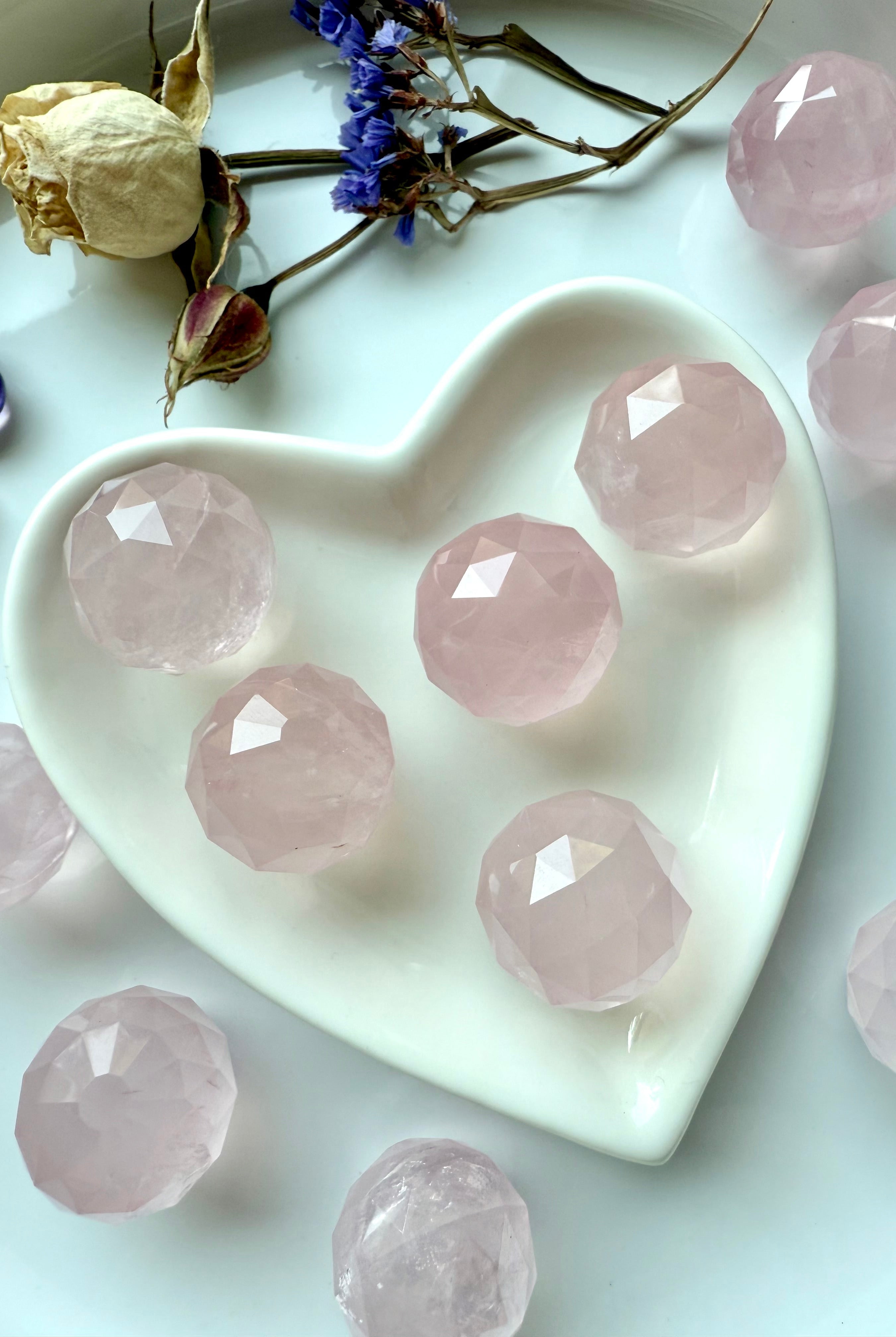 Close up of a heart-shaped dish filled with small rose quartz crystal balls for heart chakra healing.