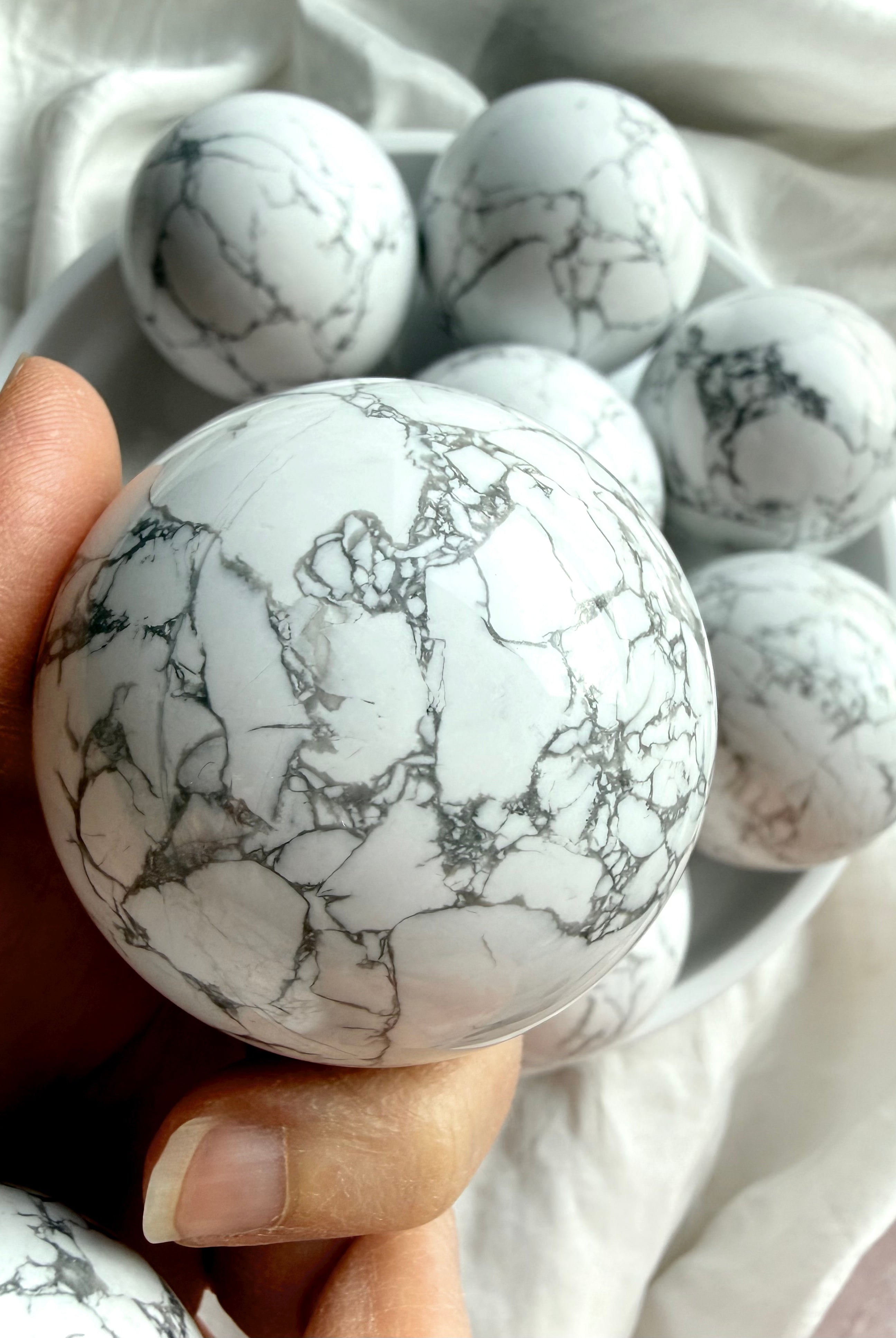 Howlite crystal ball close view in hand with intricate gray web-like veining, meditation stone for anxiety relief and mental clarity