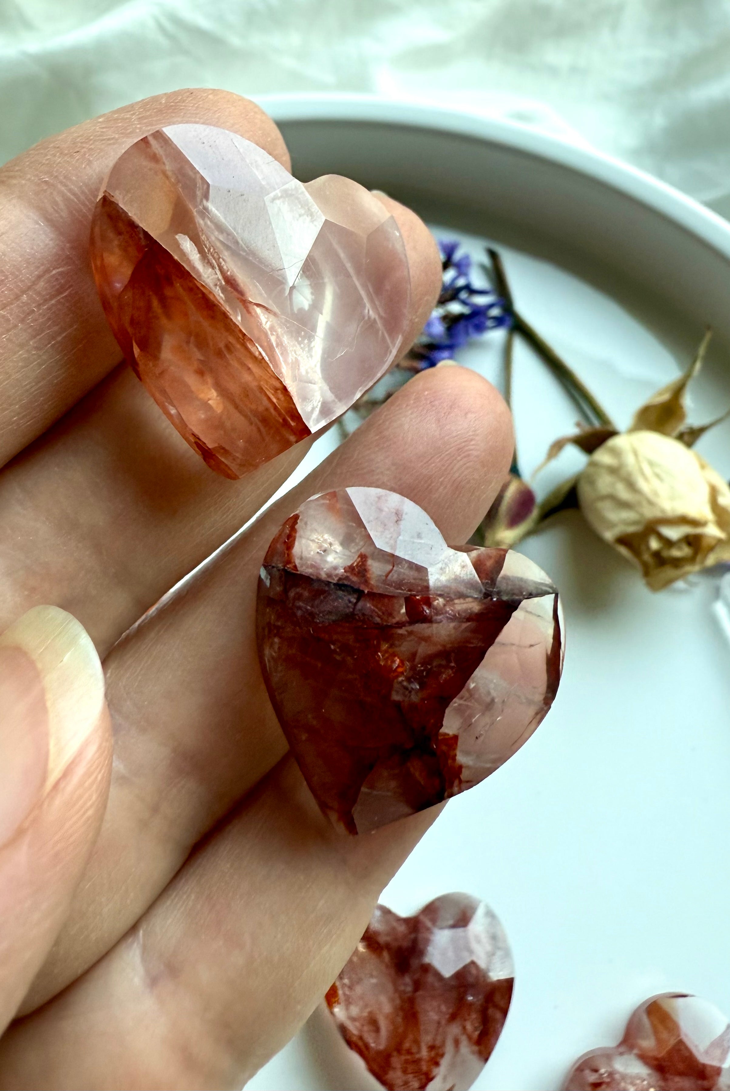 Closeup of two faceted Fire Quartz hearts – small crystal carving for energy and grounding
