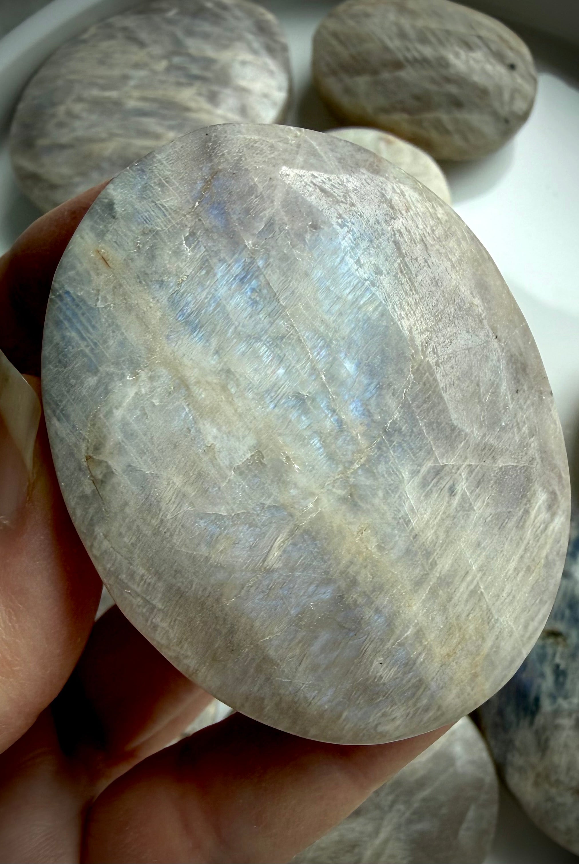 high flash belomorite moonstone palm stone with blue shimmer and natural mineral inclusions