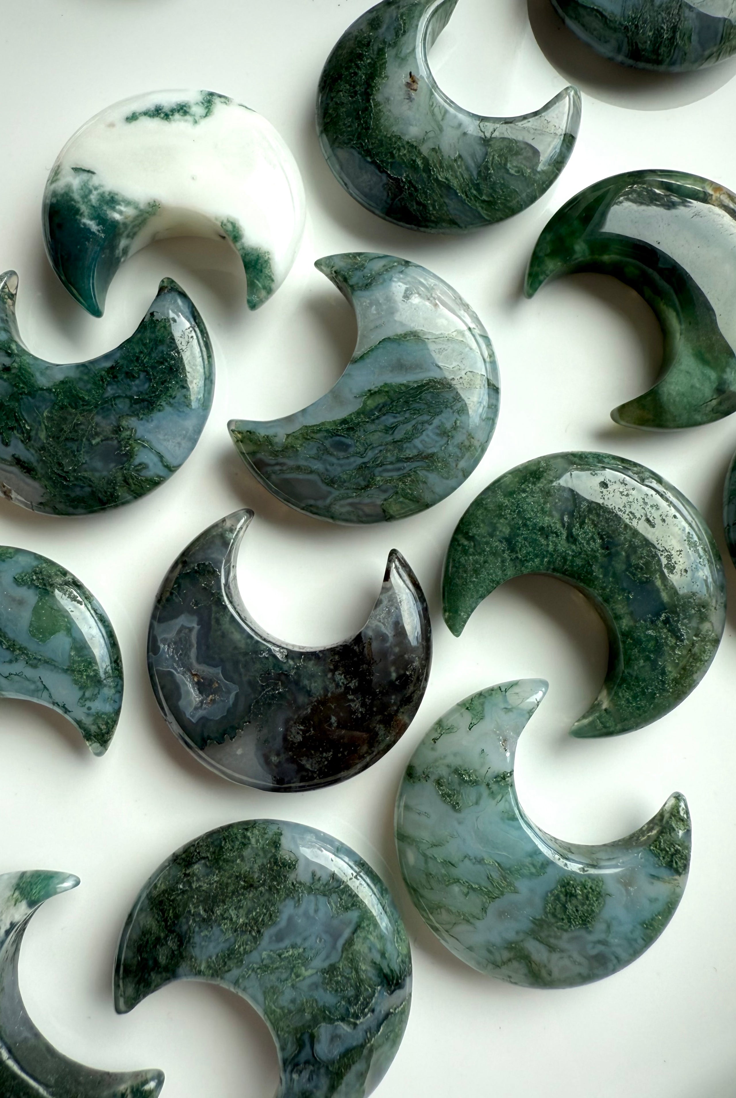 Styled flat lay of Moss Agate crescent moons for altar decor or crystal grid use.