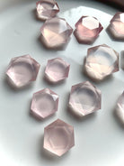 Angled closeup of faceted Rose Quartz hexagon crystals on white background, luminous pink gems for Heart Chakra love and serenity