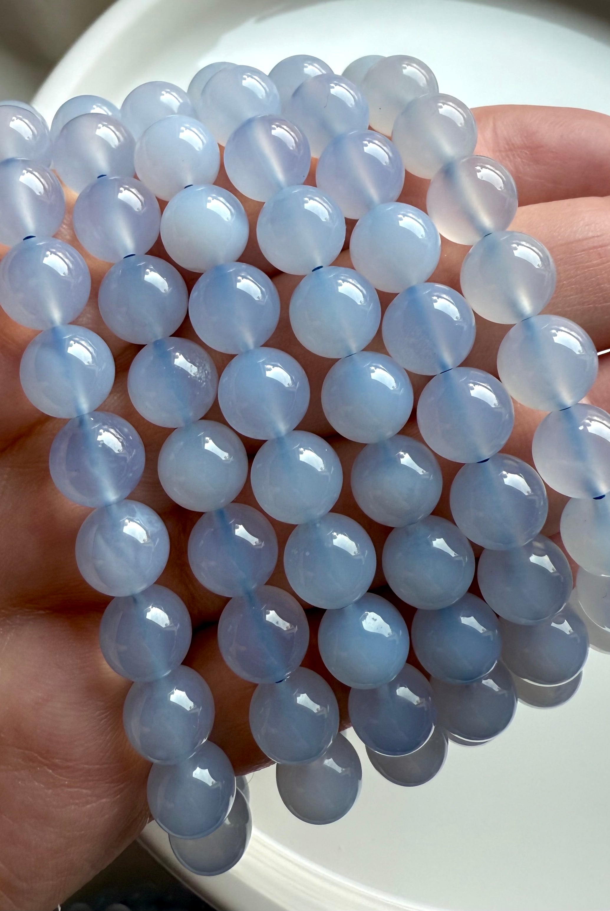 Close-up of luminous Blue Chalcedony bead bracelet in hand, showcasing soft gradients of light blue and white