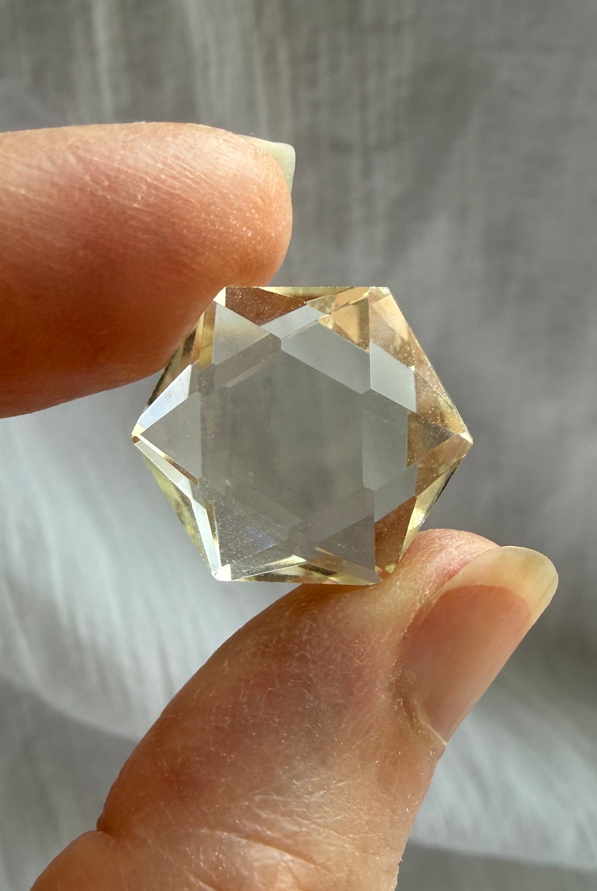 Faceted Citrine hexagon held in hand showing clear champagne-gold Quartz and precision-cut sacred geometry shape