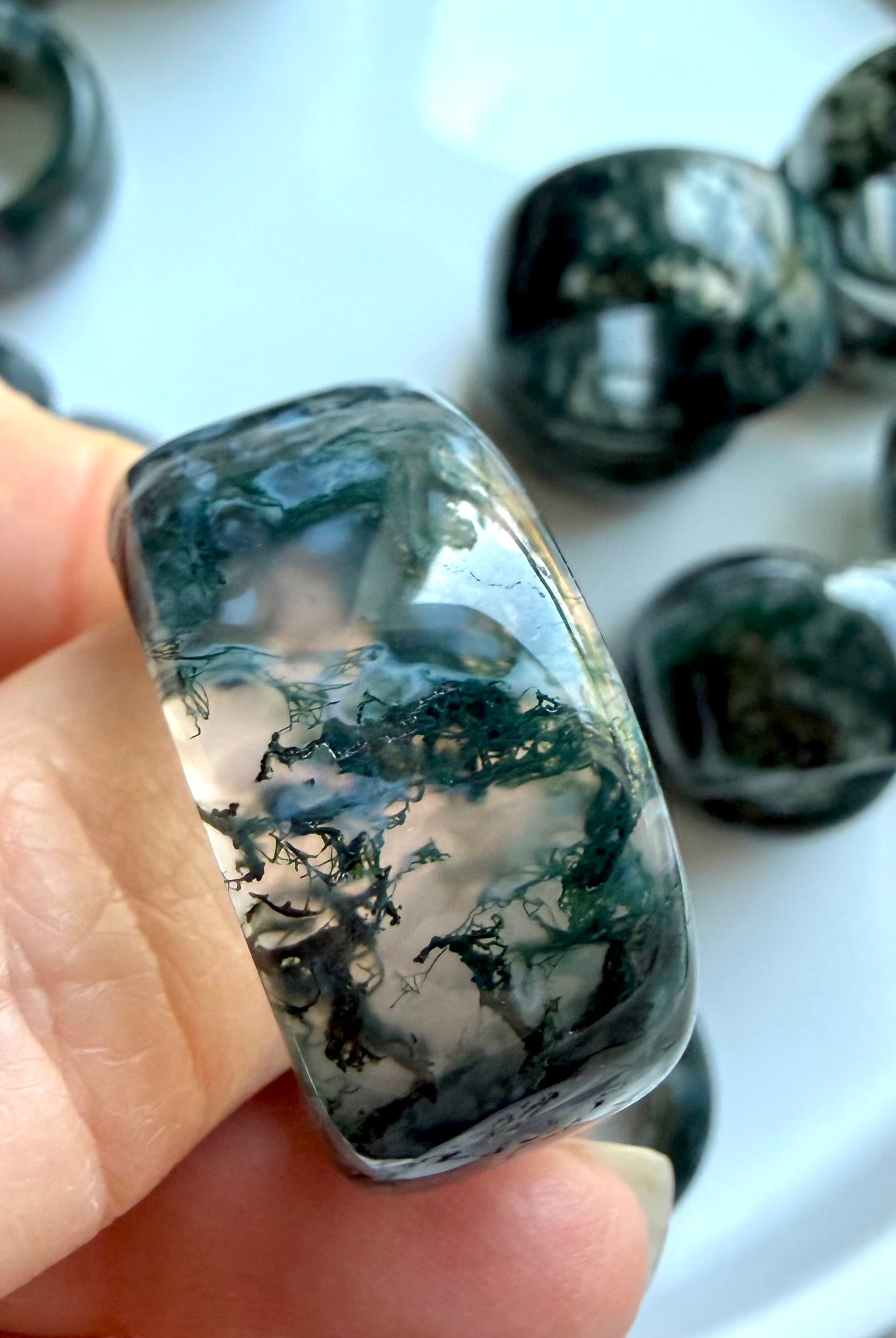 hand holding thick moss agate crystal ring closeup showing natural moss-like inclusions and earthy grounding tones