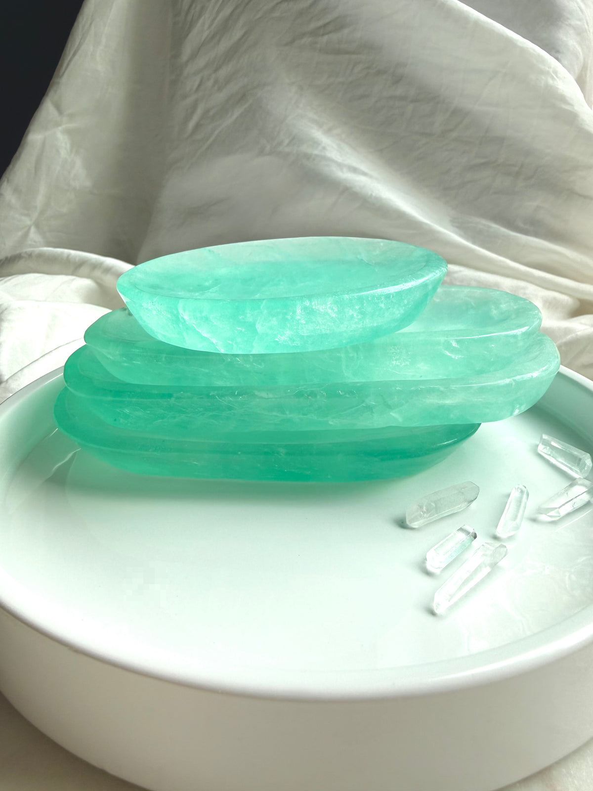 Stack of polished Green Fluorite crystal bowls showing shallow profile, saturated color, and translucent stone