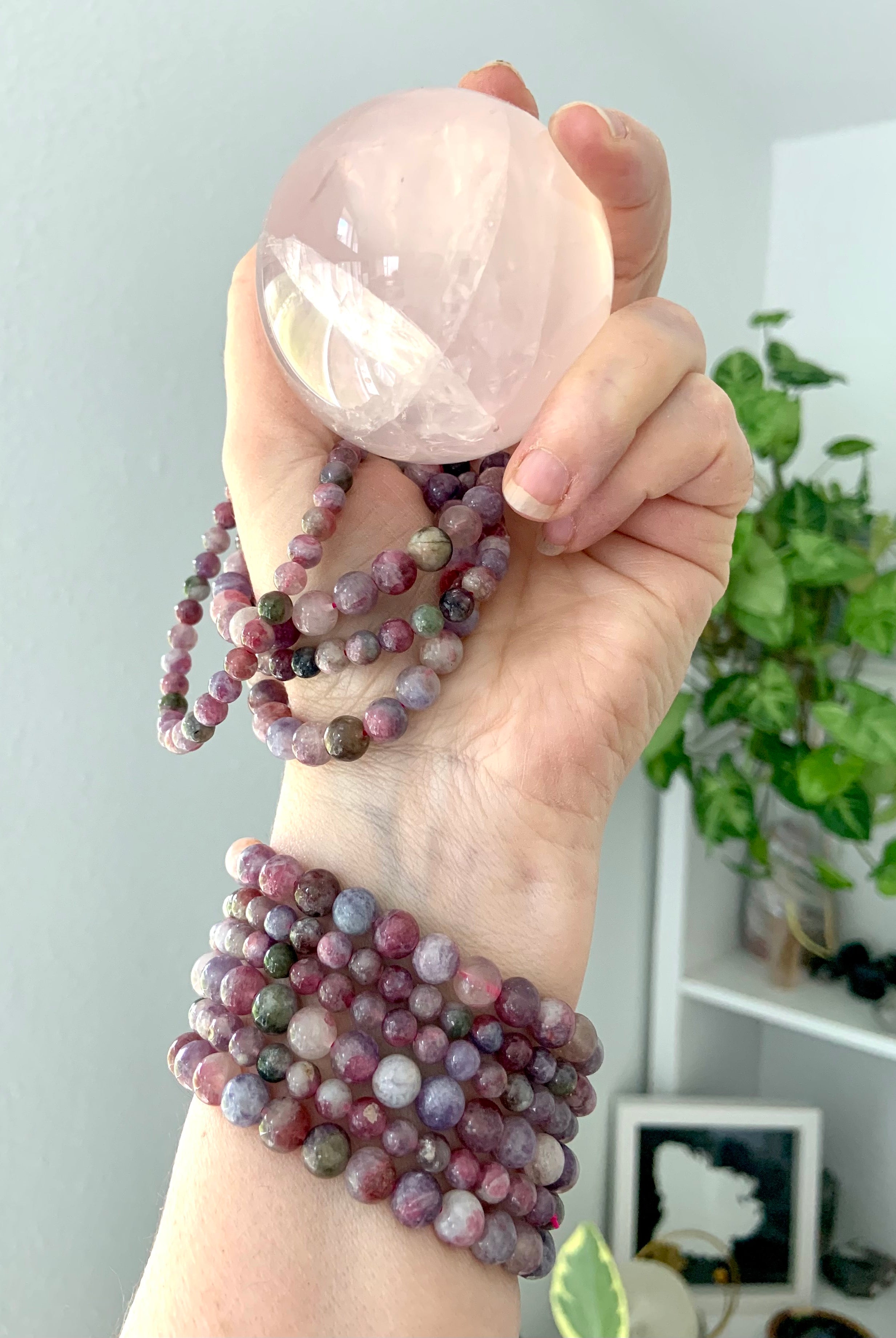 Green Unicorn Stone bracelets — aka Watermelon Tourmaline in Lepidolite — stacked on wrist and held with rose quartz sphere. Heart chakra jewelry for love, grief support + calm