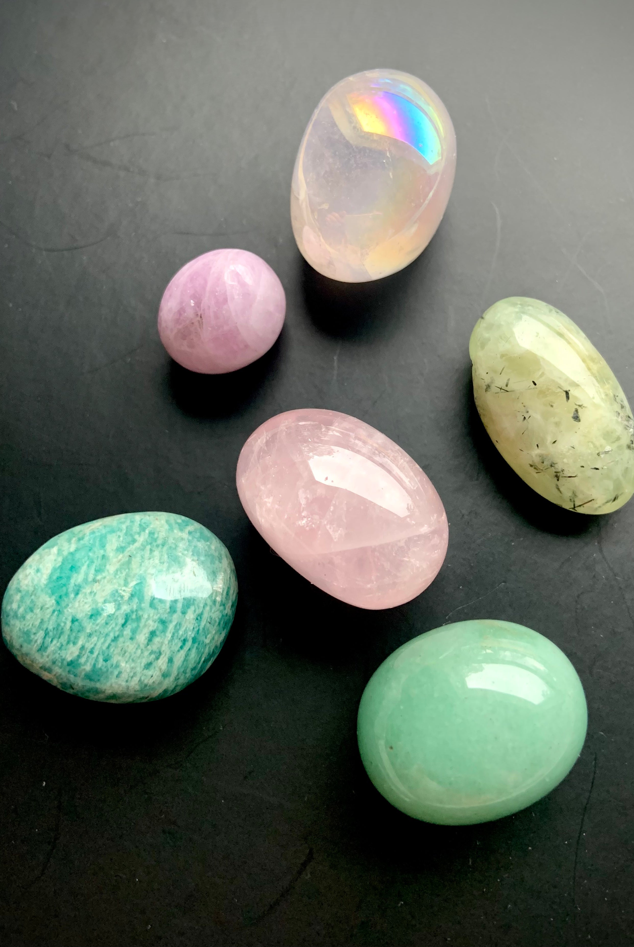 Close-up of Heart Chakra crystal set of 7 healing stones on a black background — glowing pink and green chakra stones for emotional balance and compassion.