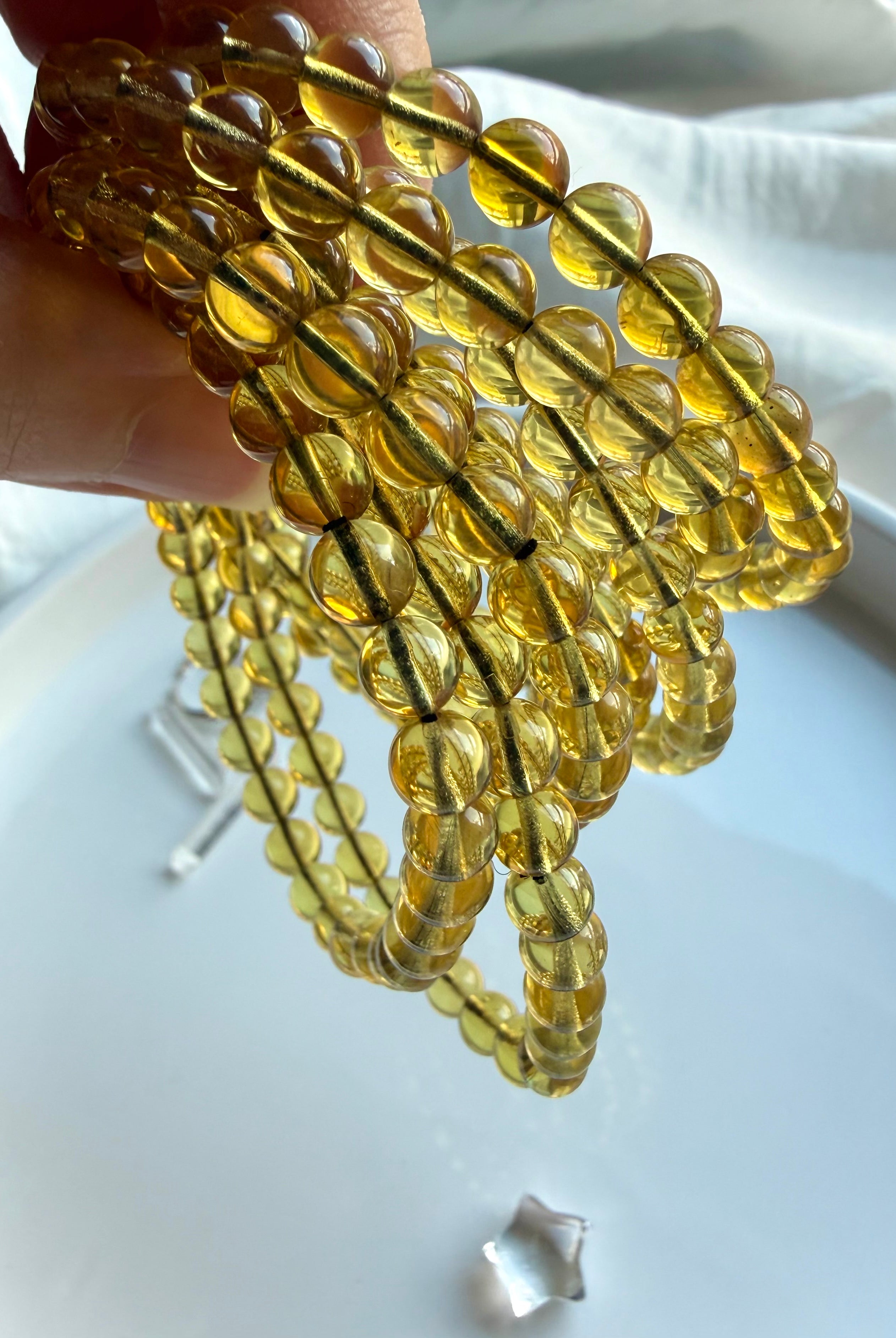 Natural Indonesian blue amber bead bracelets held to the light – golden amber crystal jewelry