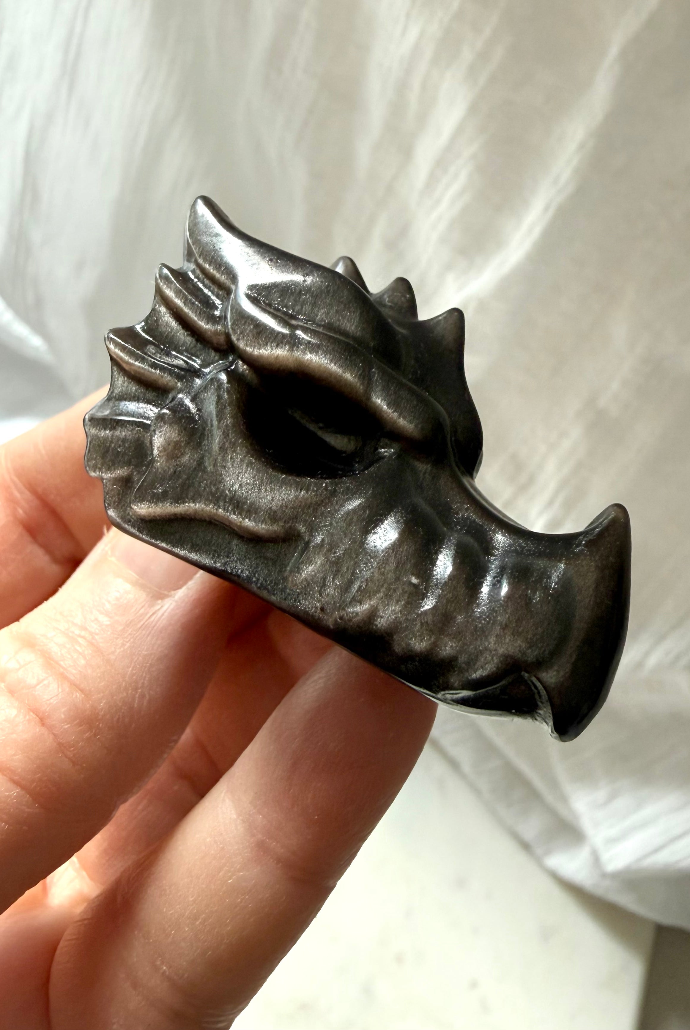 angled view of silver sheen obsidian dragon carving showing sculpted details and high-gloss finish, grounding crystal for shadow integration