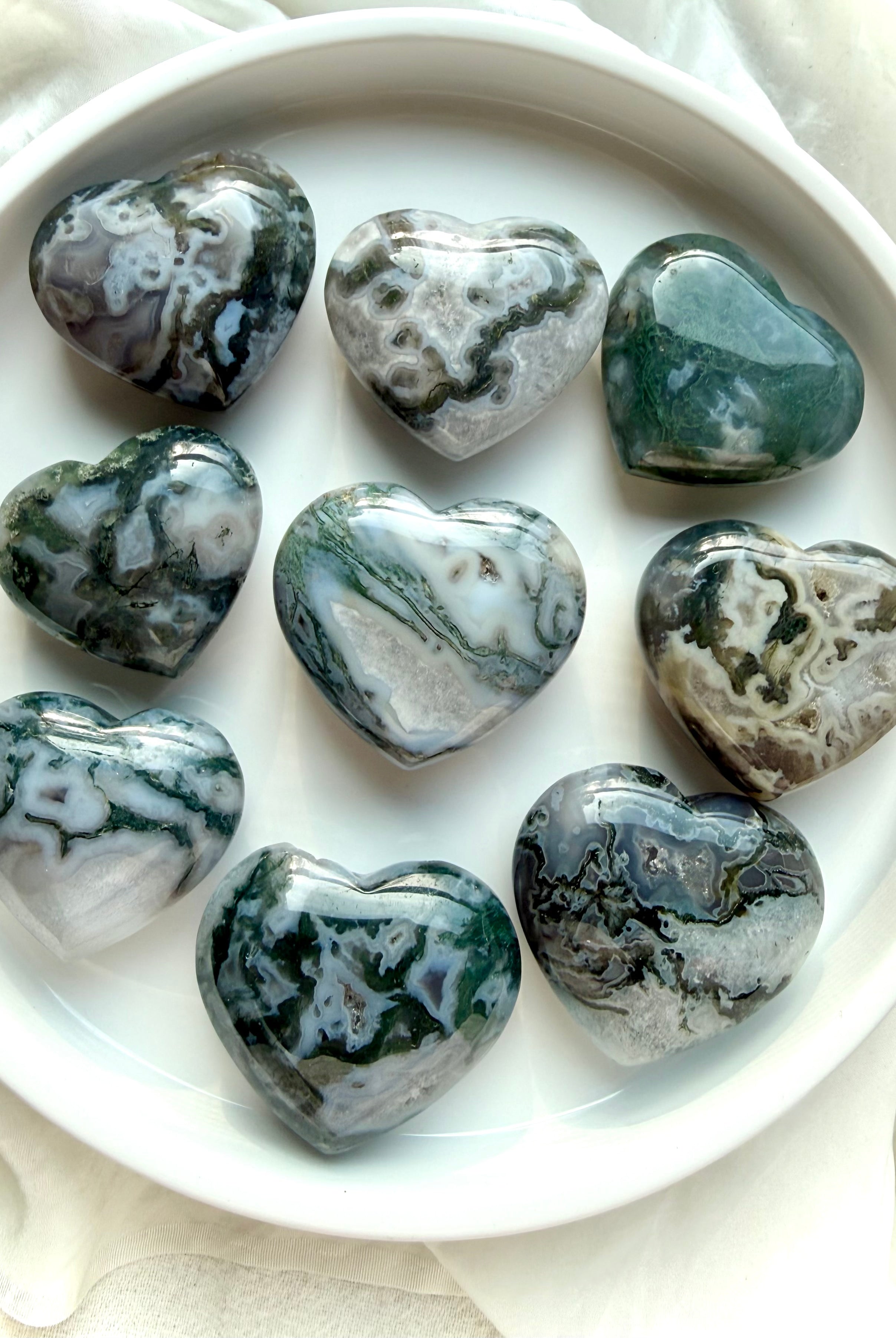 moss agate heart carvings on ceramic tray with natural green moss inclusions and polished crystal surfaces