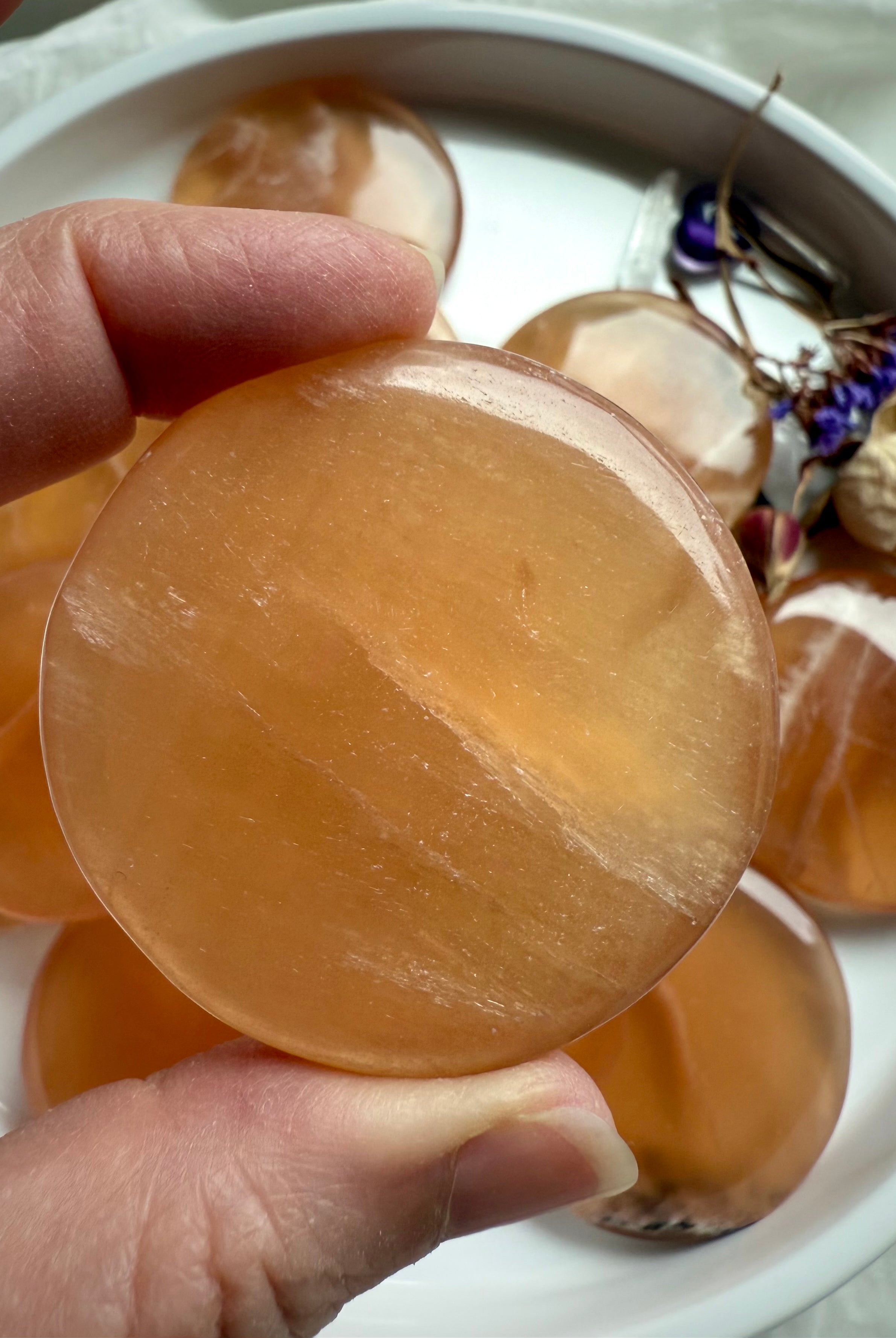Polished honey calcite disc with golden translucence and subtle banding, held in natural light to highlight its radiant Solar Plexus energy.