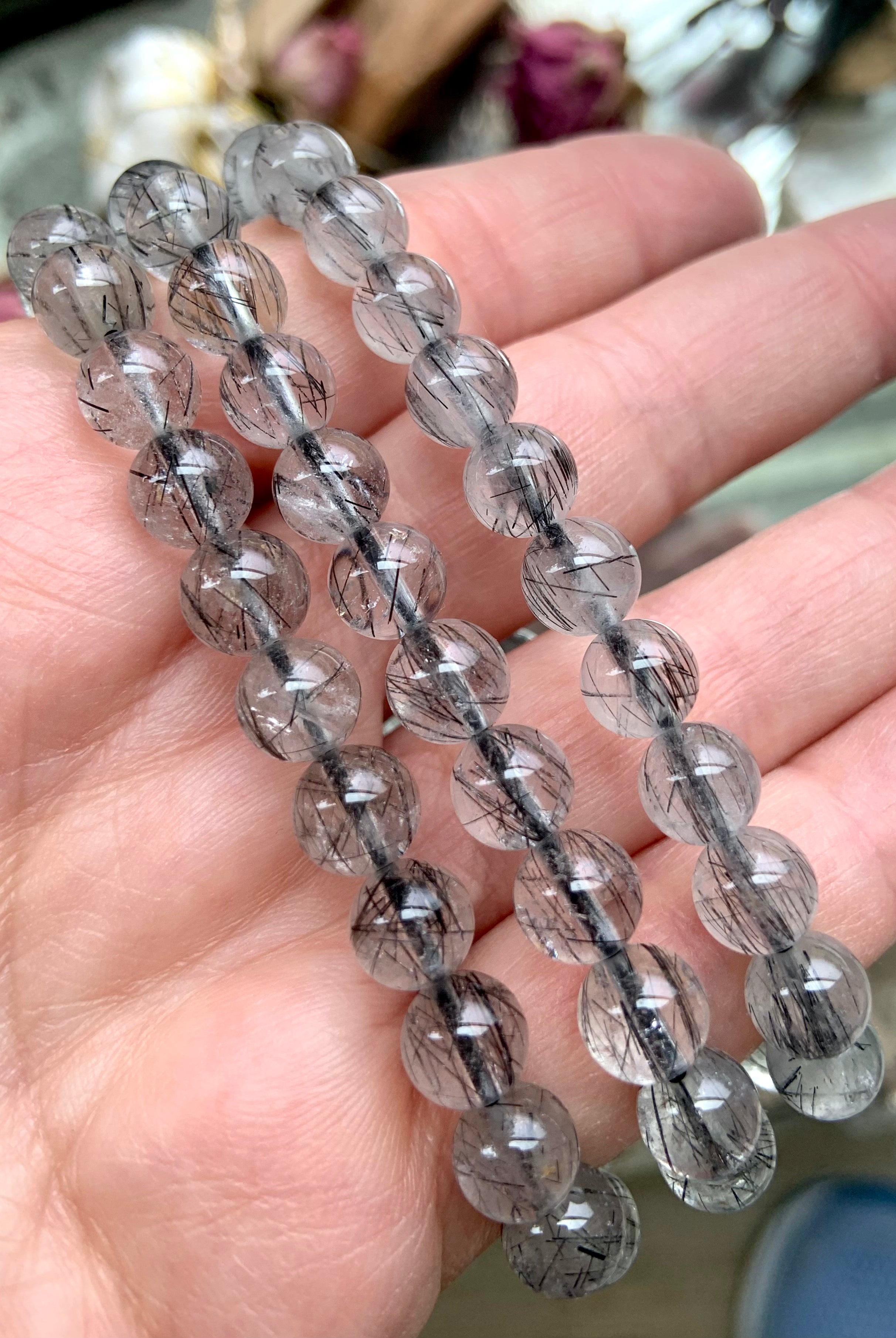 Three high-quality Black Tourmaline in Quartz bracelets displayed on a hand, highlighting the clarity and delicate needle-like black tourmaline strands