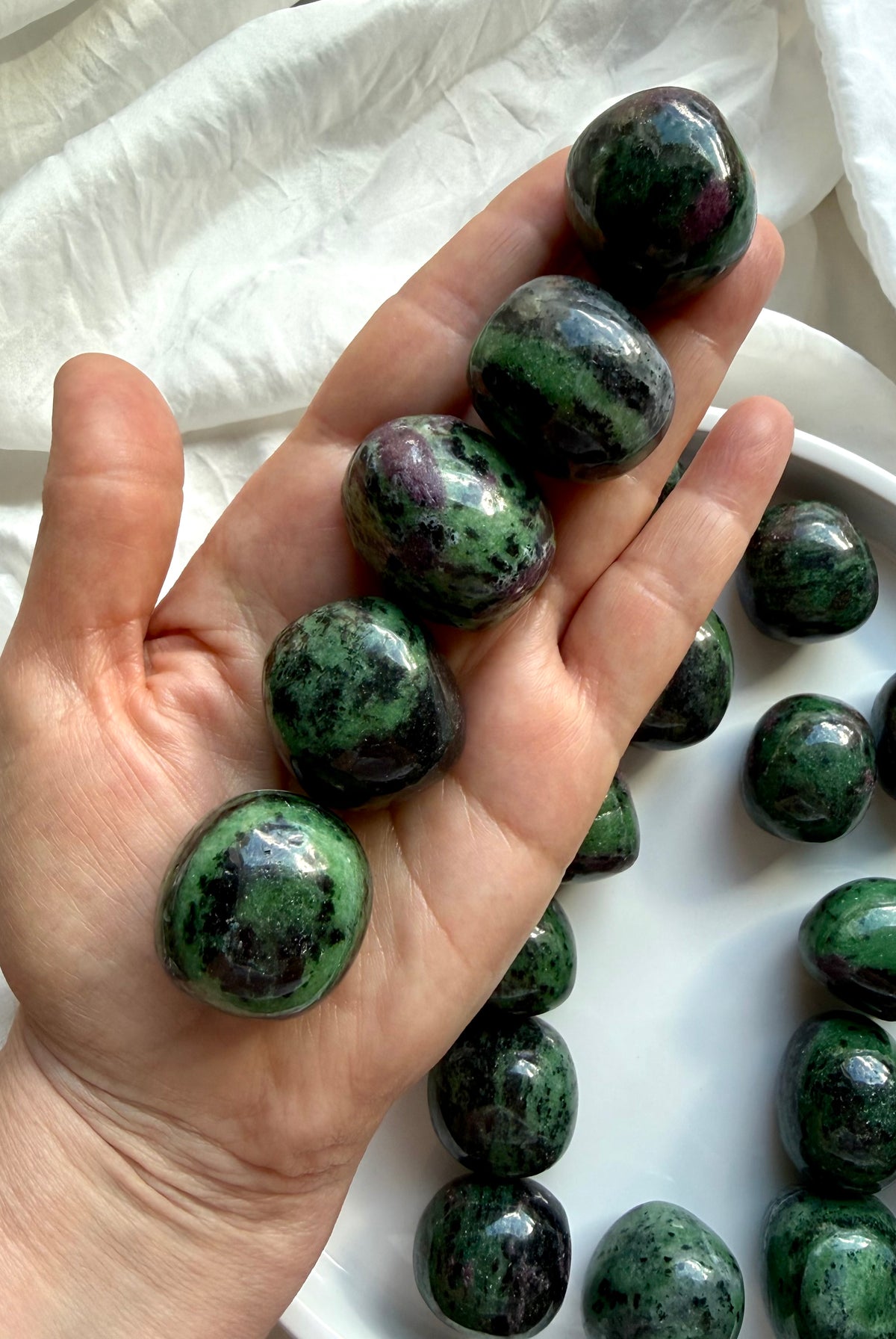 Ruby Zoisite healing crystals held in hand, polished green and ruby pink tumbled stones for passion, courage and emotional balance