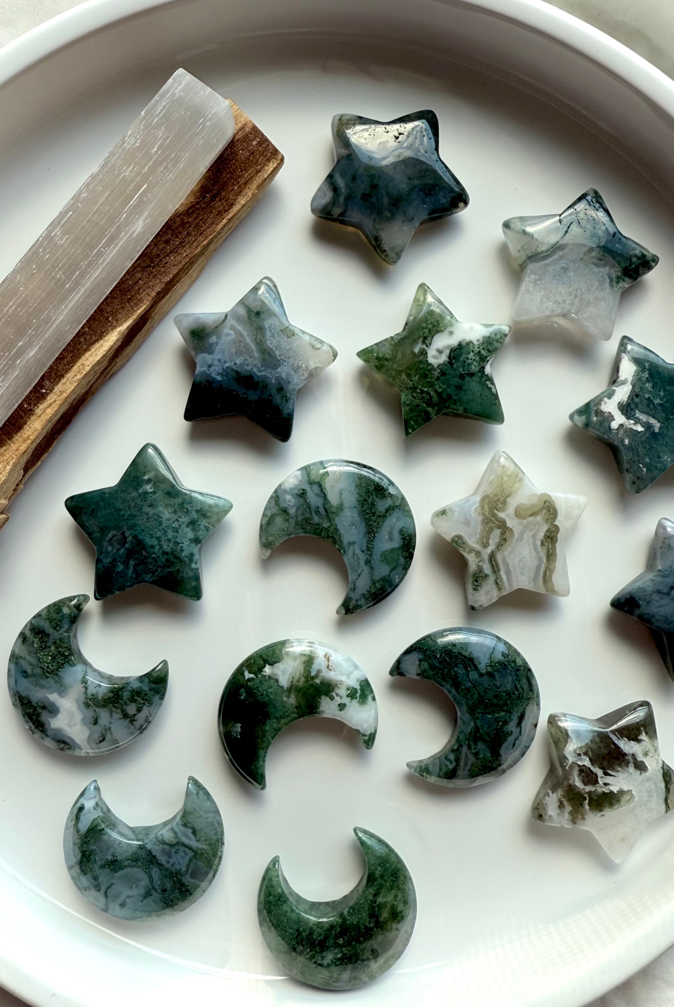 Moss Agate stars and crescent moons displayed with selenite and palo santo — grounding crystal shapes for meditation, cleansing, and Earth connection rituals.