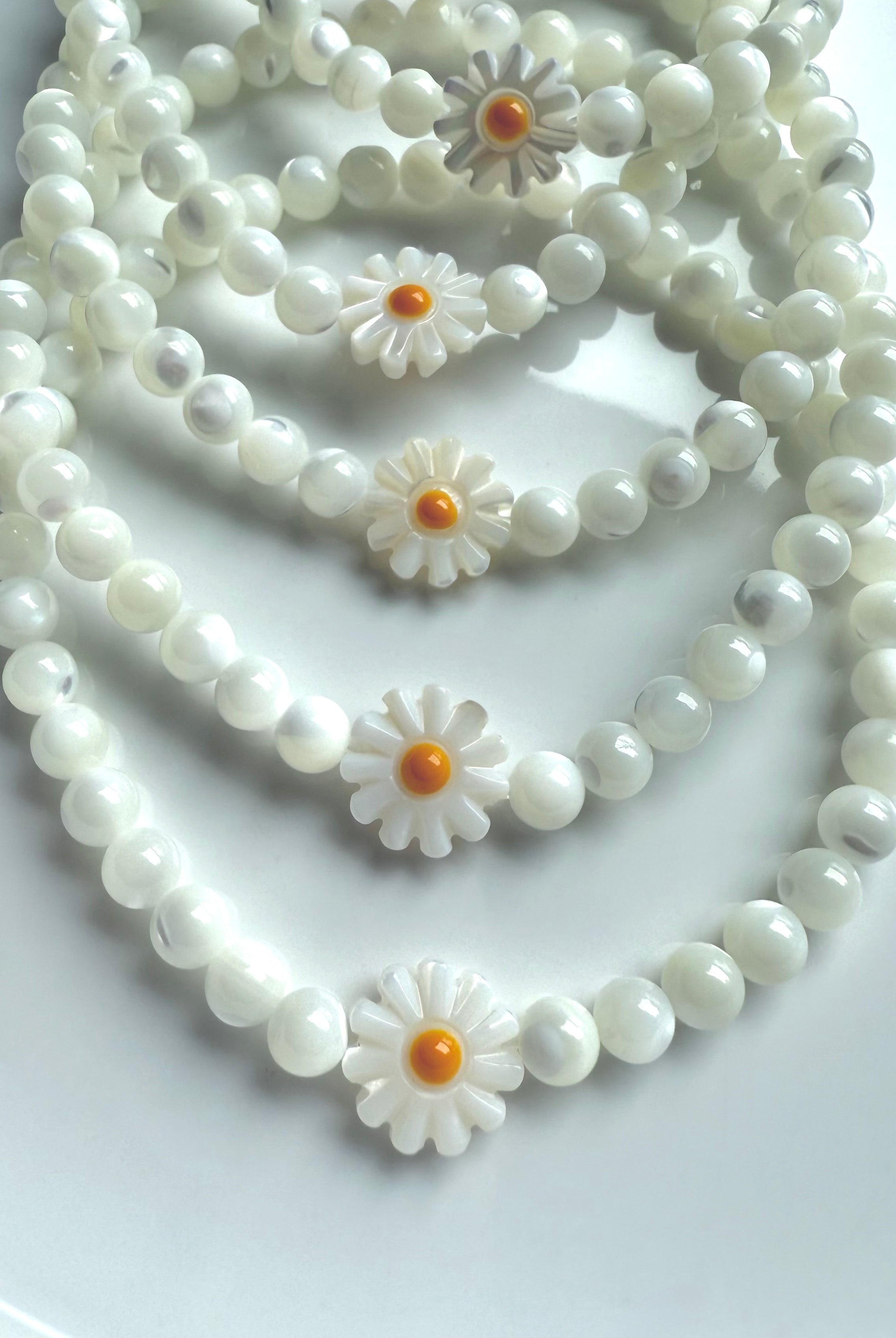 Close-up of daisy bead design on Mother of Pearl bracelet, showcasing glowing shell beads and carved flower detail