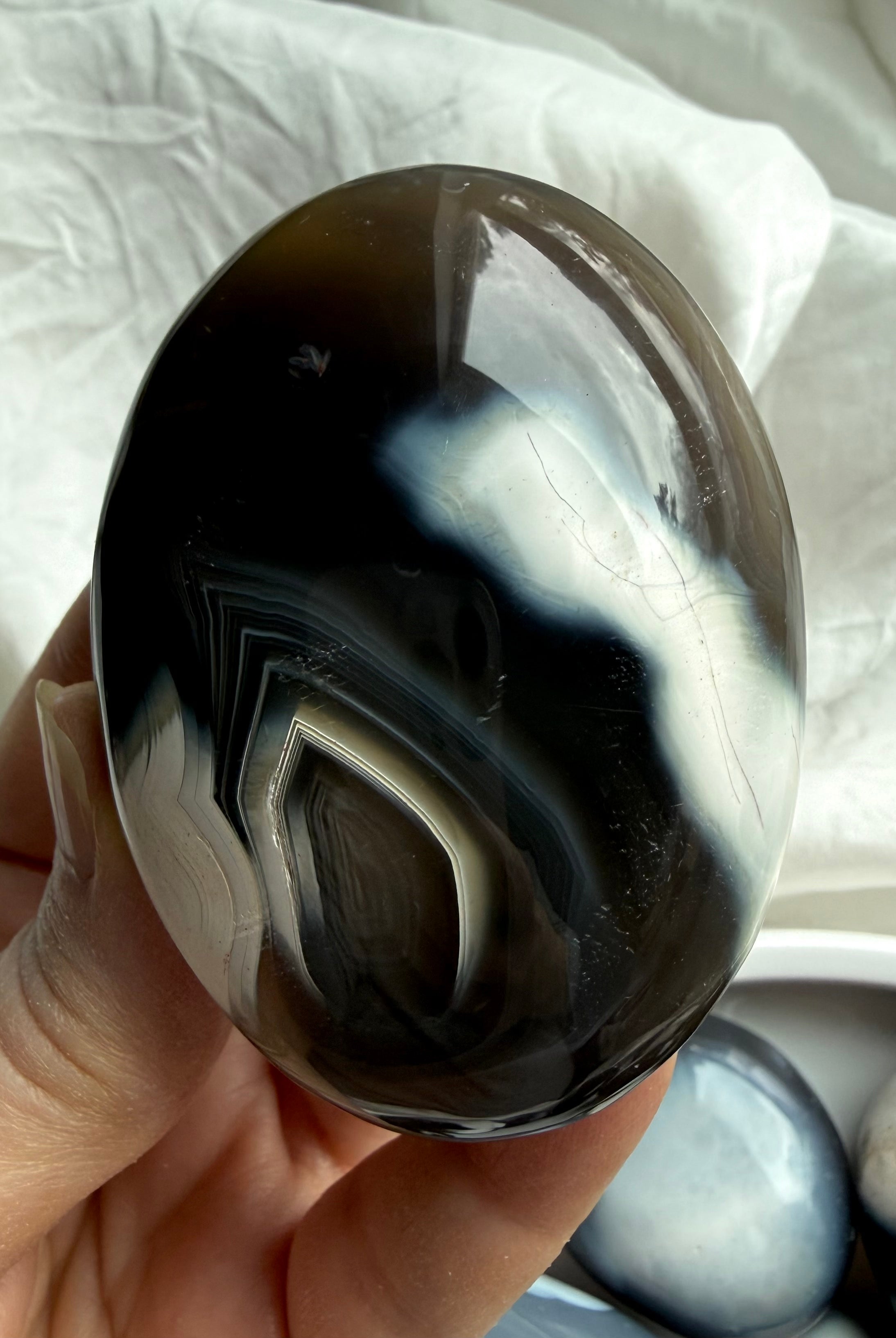 Orca Agate palm stone held in hand, highlighting smooth polish and layered black and white agate patterns for grounding energy