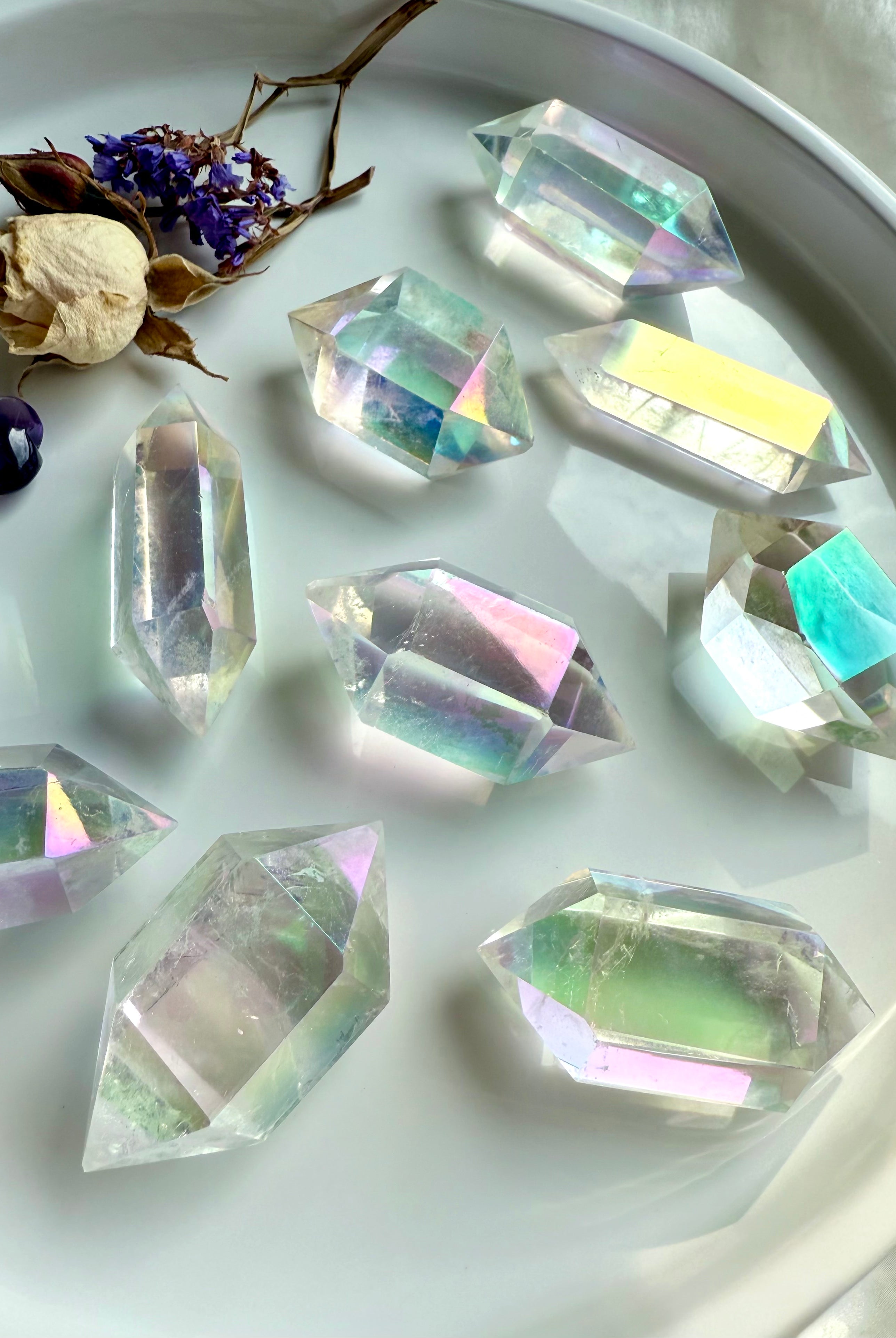 Collection of Angel Aura Quartz double terminated points arranged in a round dish with dried flowers and amethyst accent