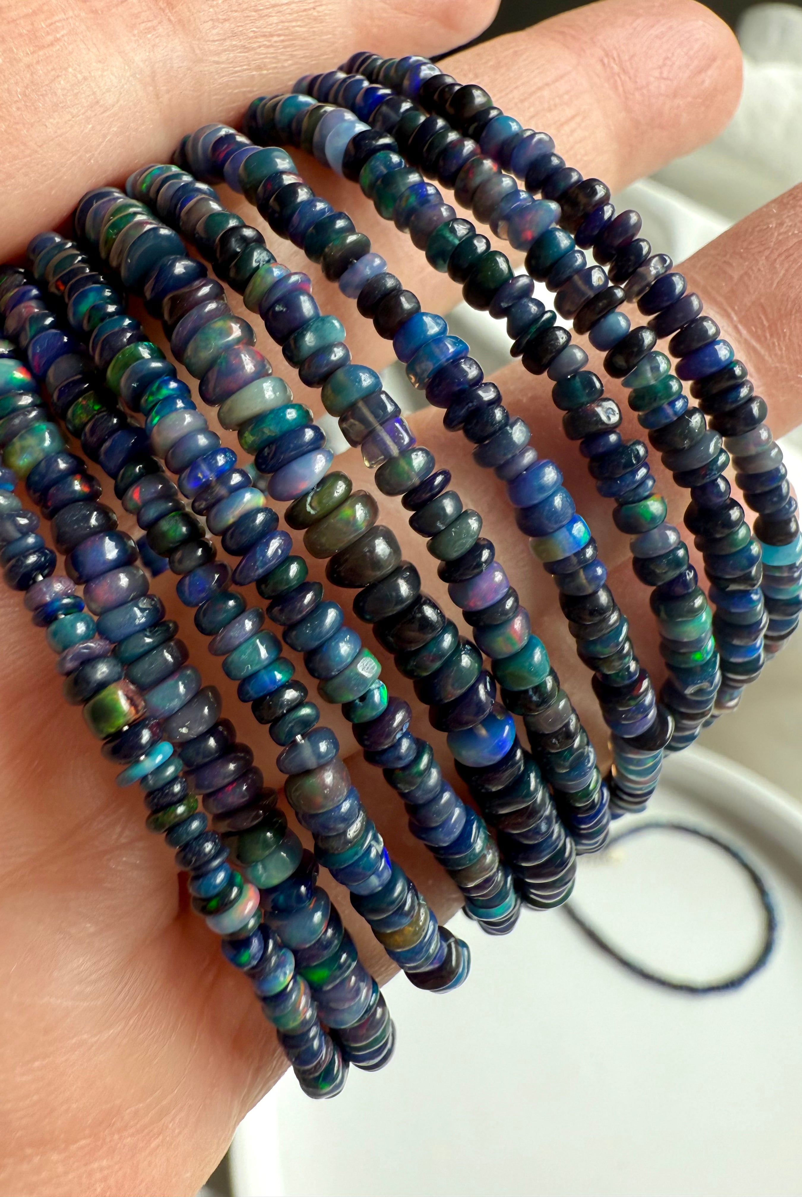 Detail shot showing rainbow flash — Close-up of luminous Black Fire Opal beads with sterling silver clasp — real opal jewelry.