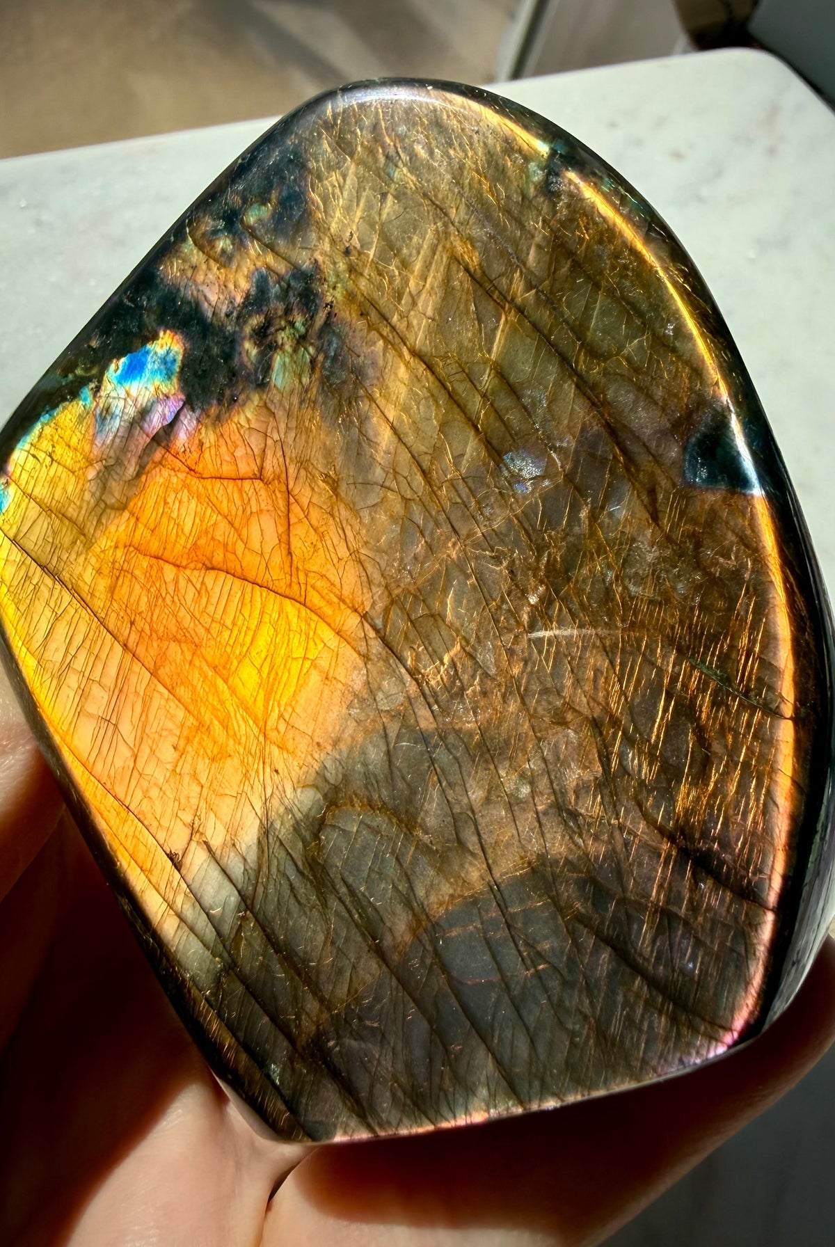 Orange Labradorite crystal showing glowing copper flash with pink, purple and blue accents