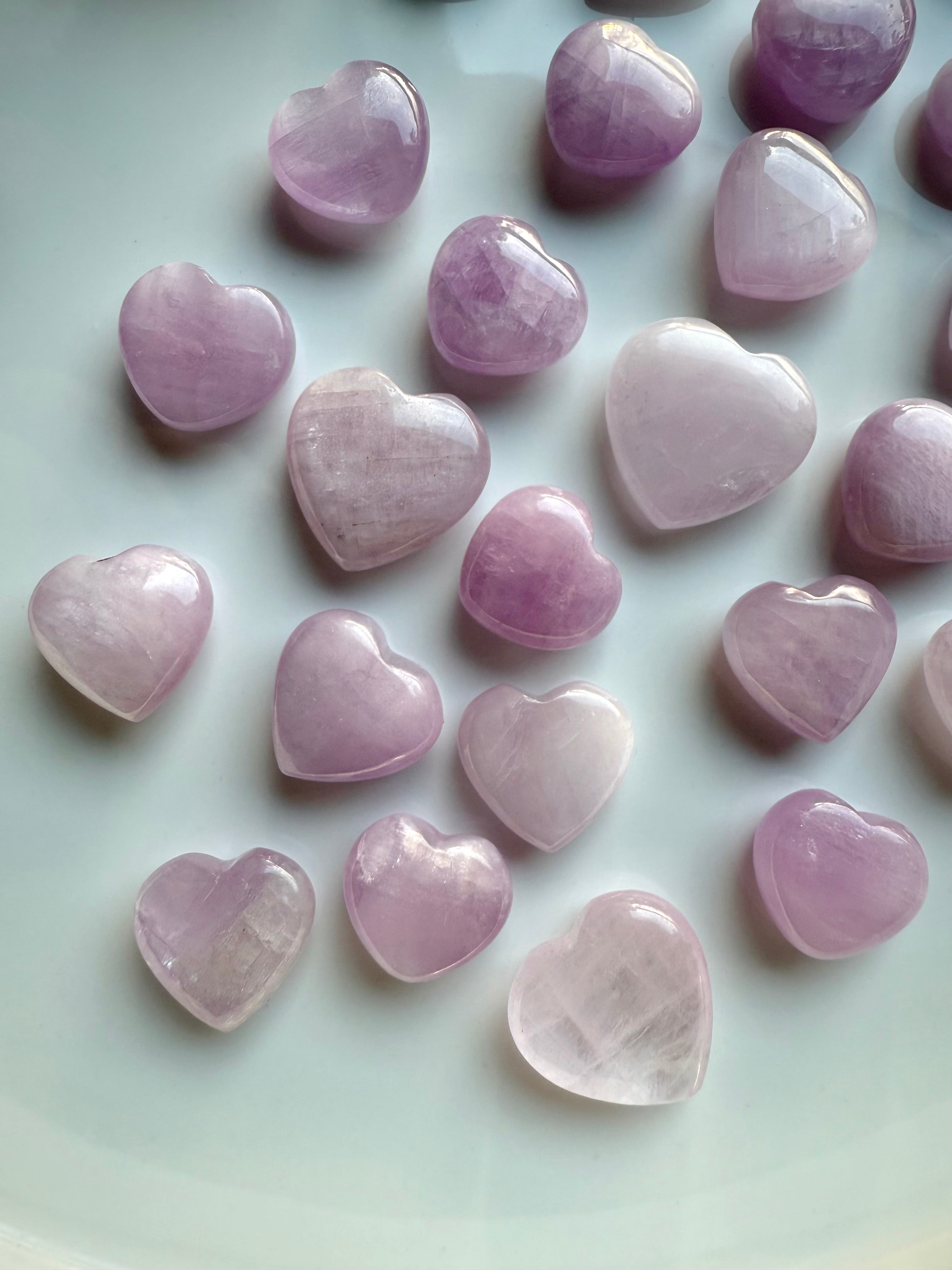 Close-up of mini Pink Kunzite hearts on a white background β crystal hearts for peace, compassion & energetic balance.