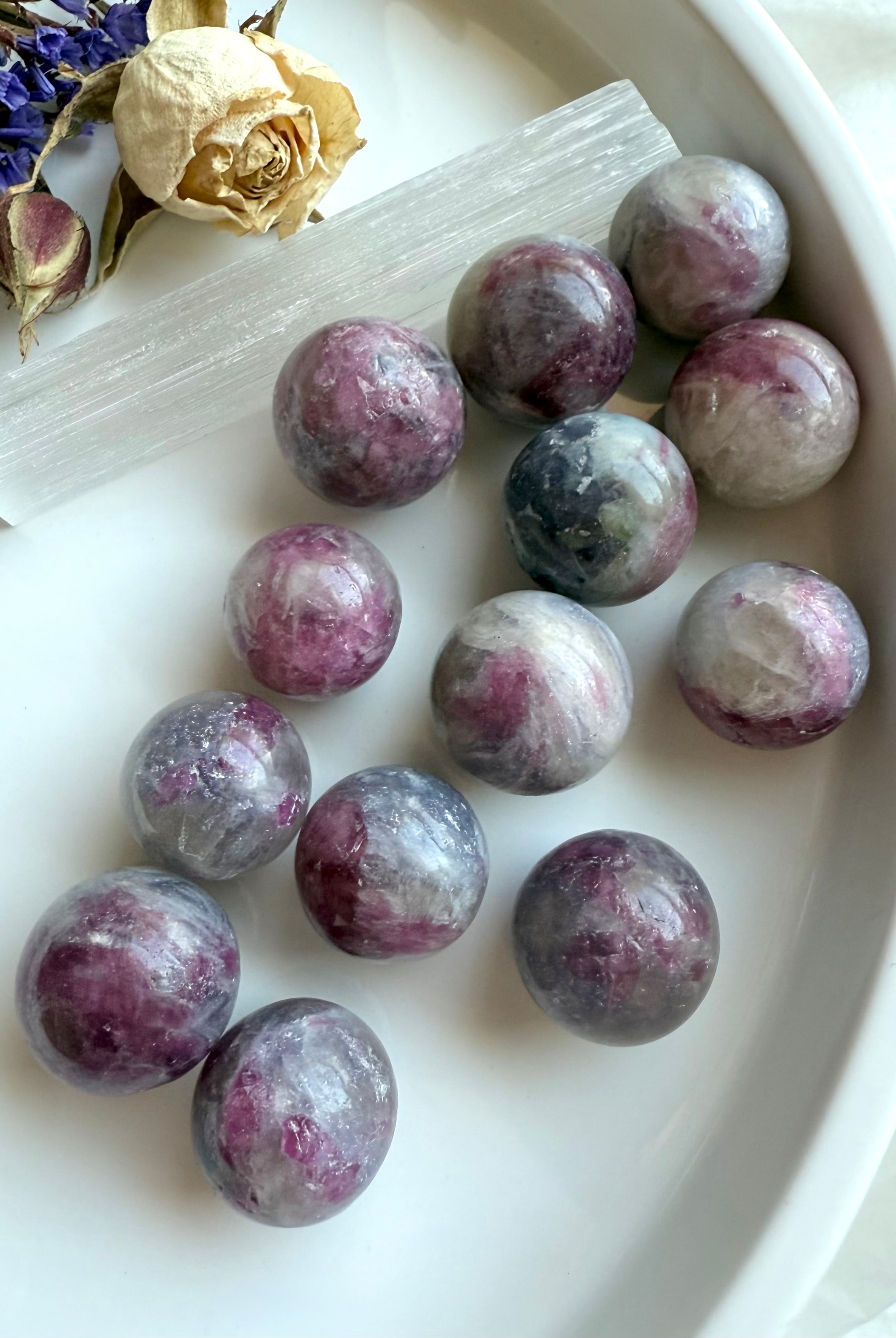 Unicorn Stone crystal spheres on a white plate, showing soothing patterns of pink and purple colors