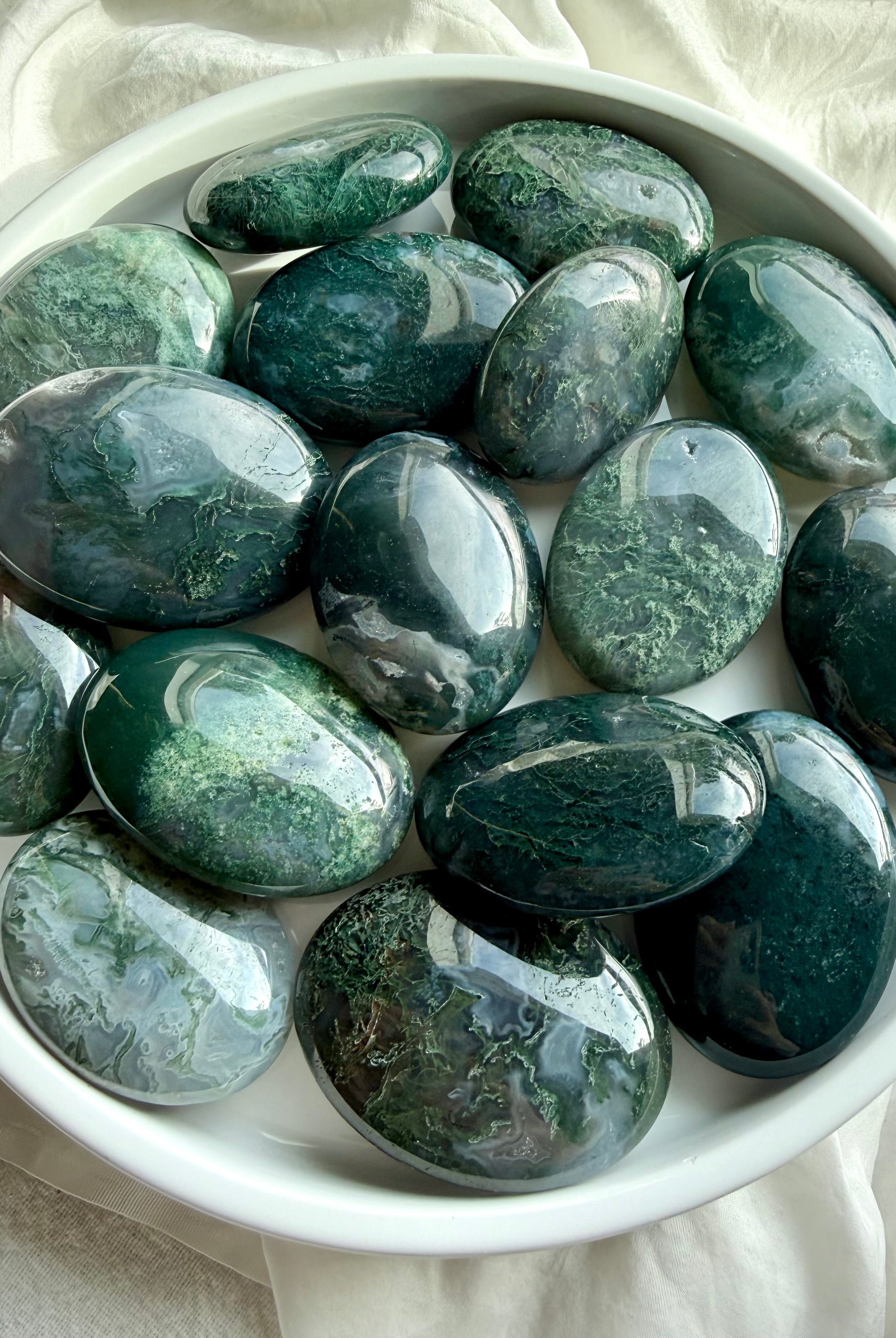 Polished moss agate palm stones showing natural green inclusions and earthy patterns, grounding crystals for stress relief