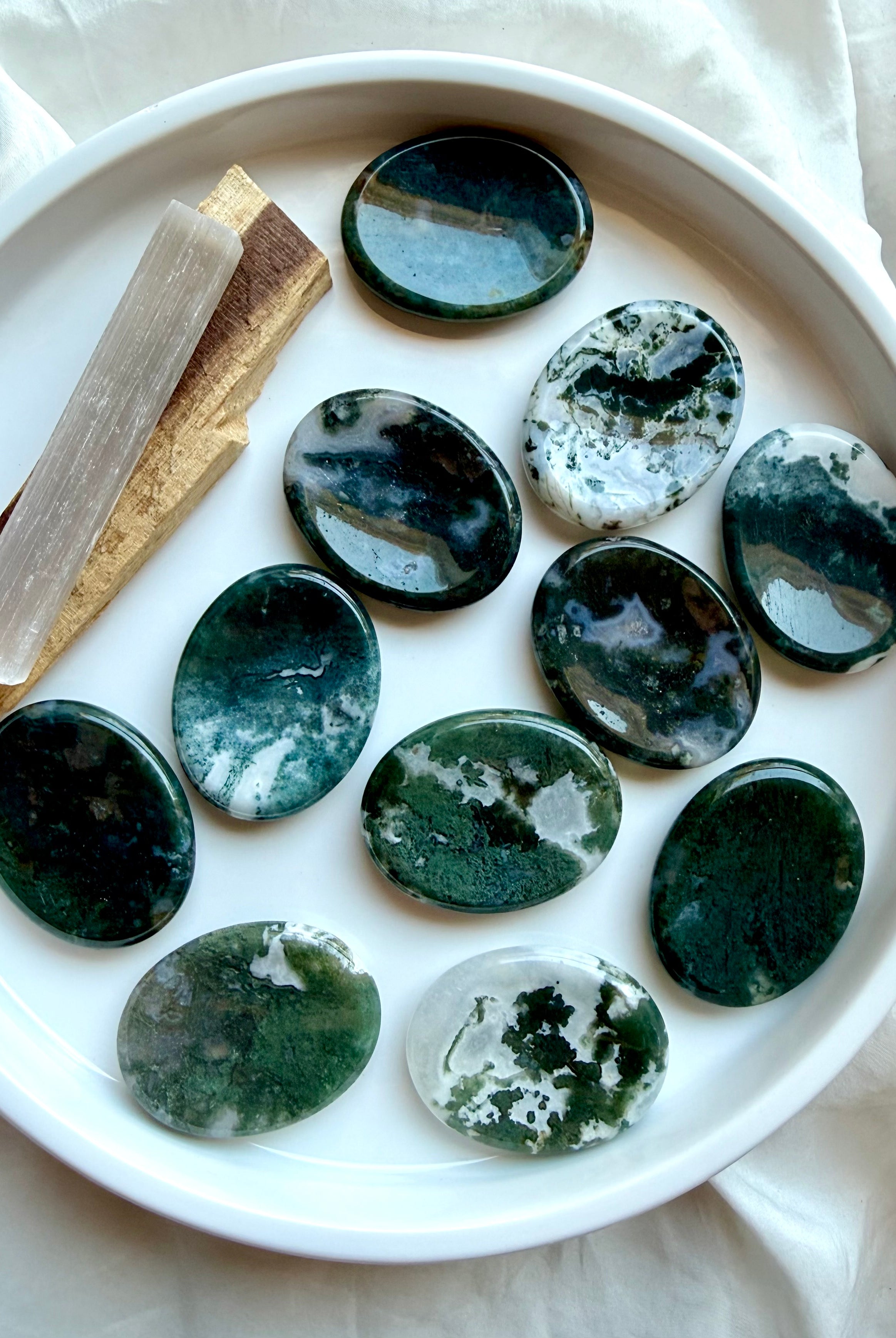 Moss Agate oval touchstones displayed on a white plate with polished finish and natural moss patterns