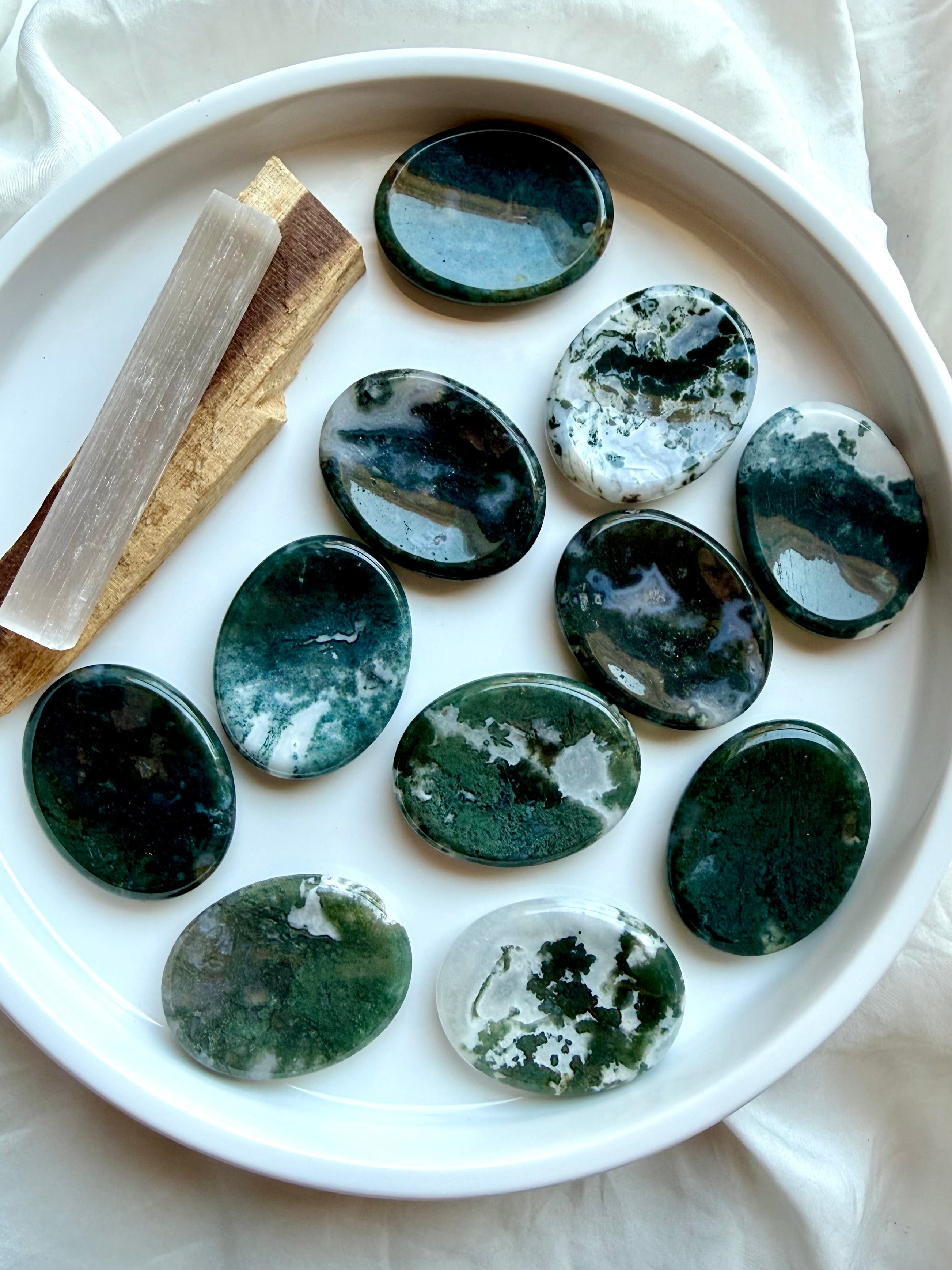 Moss Agate oval touchstones displayed on a white plate with polished finish and natural moss patterns
