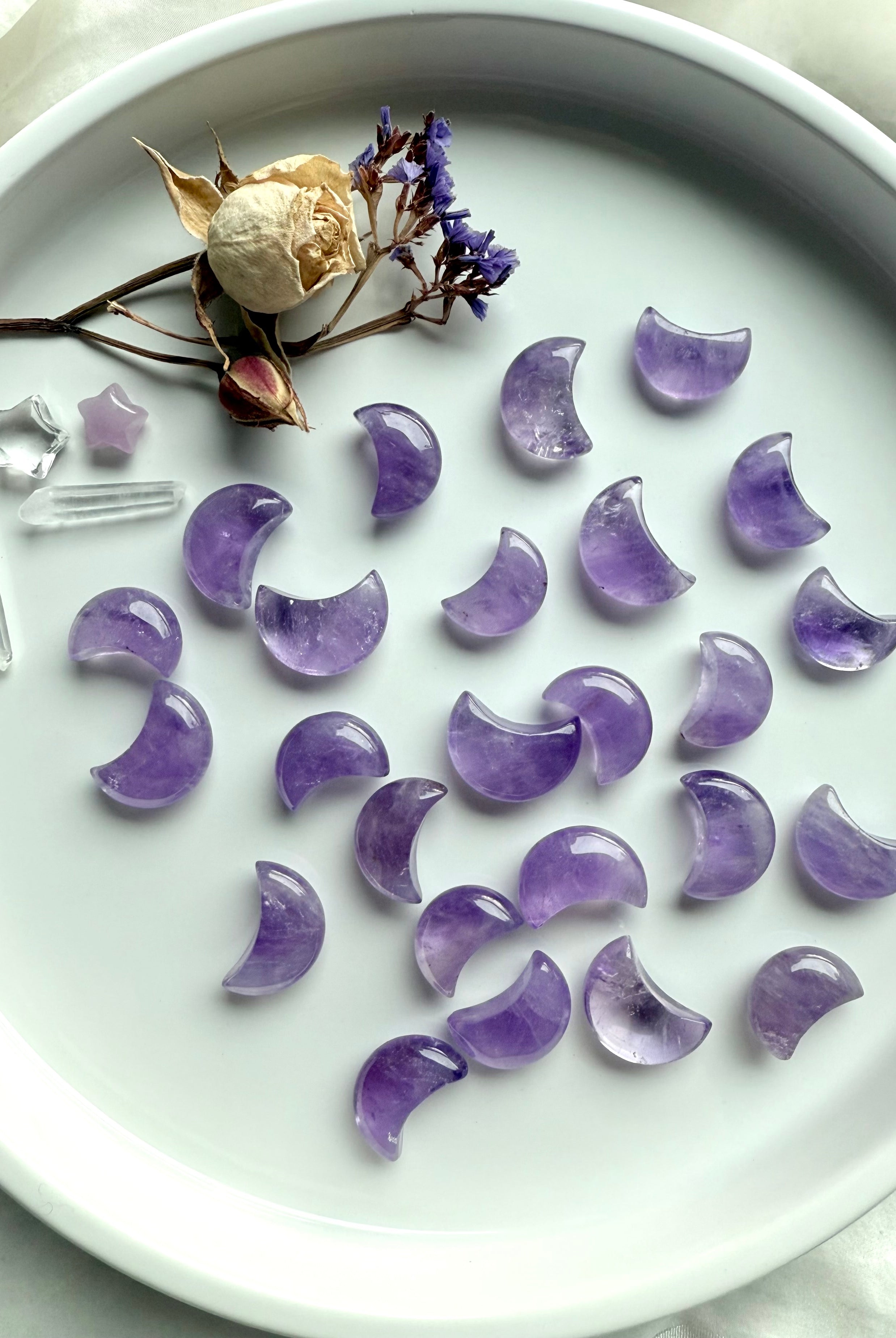 Small amethyst moon crystals scattered with crystal points and dried flowers