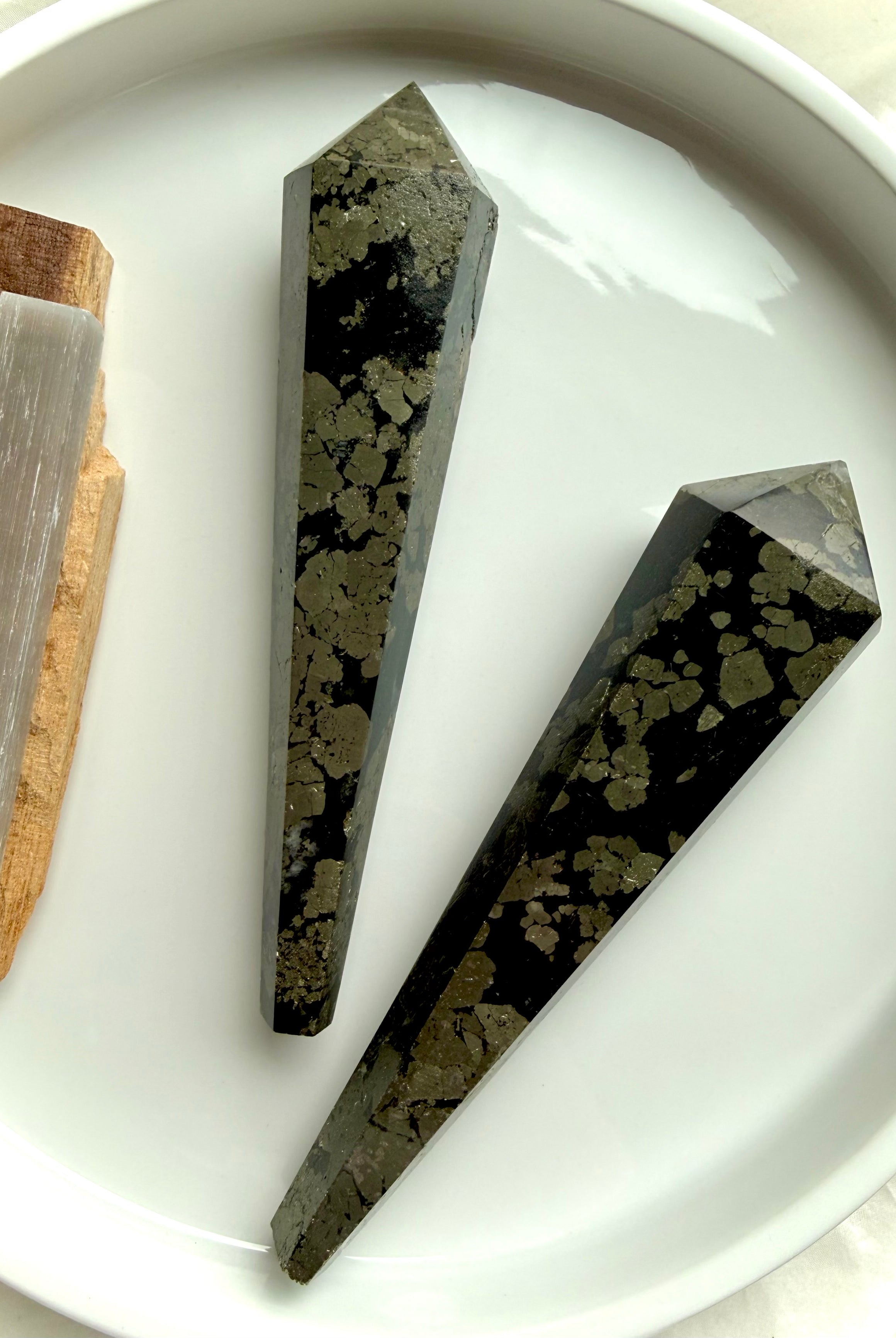 two pyrite wands in black matrix on white tray polished crystal points