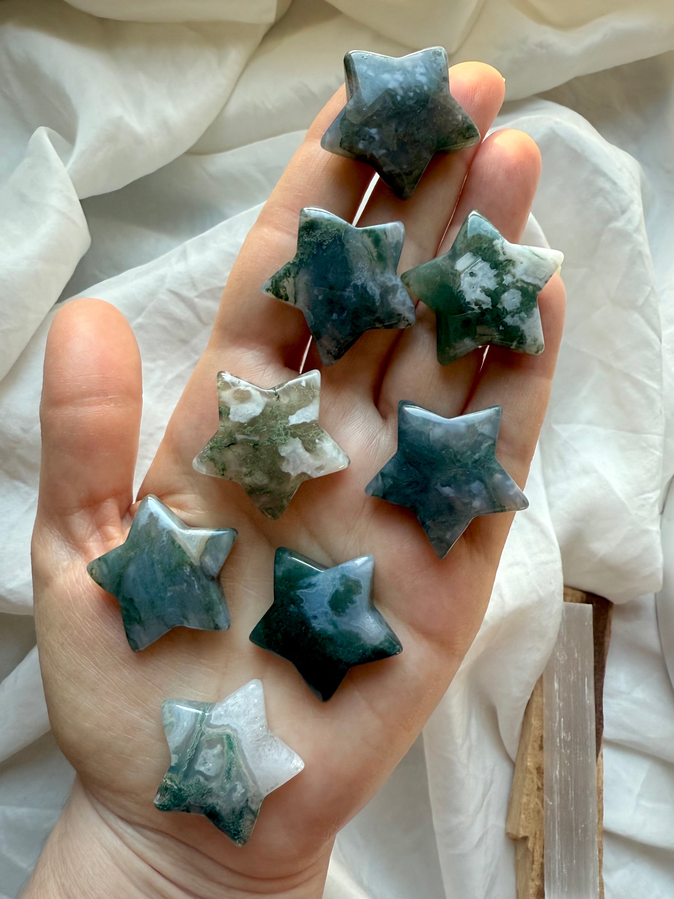 Moss Agate crystal stars shown in hand, displaying natural green moss patterns and white swirls — heart chakra healing stone for grounding, peace, and Gaia connection.