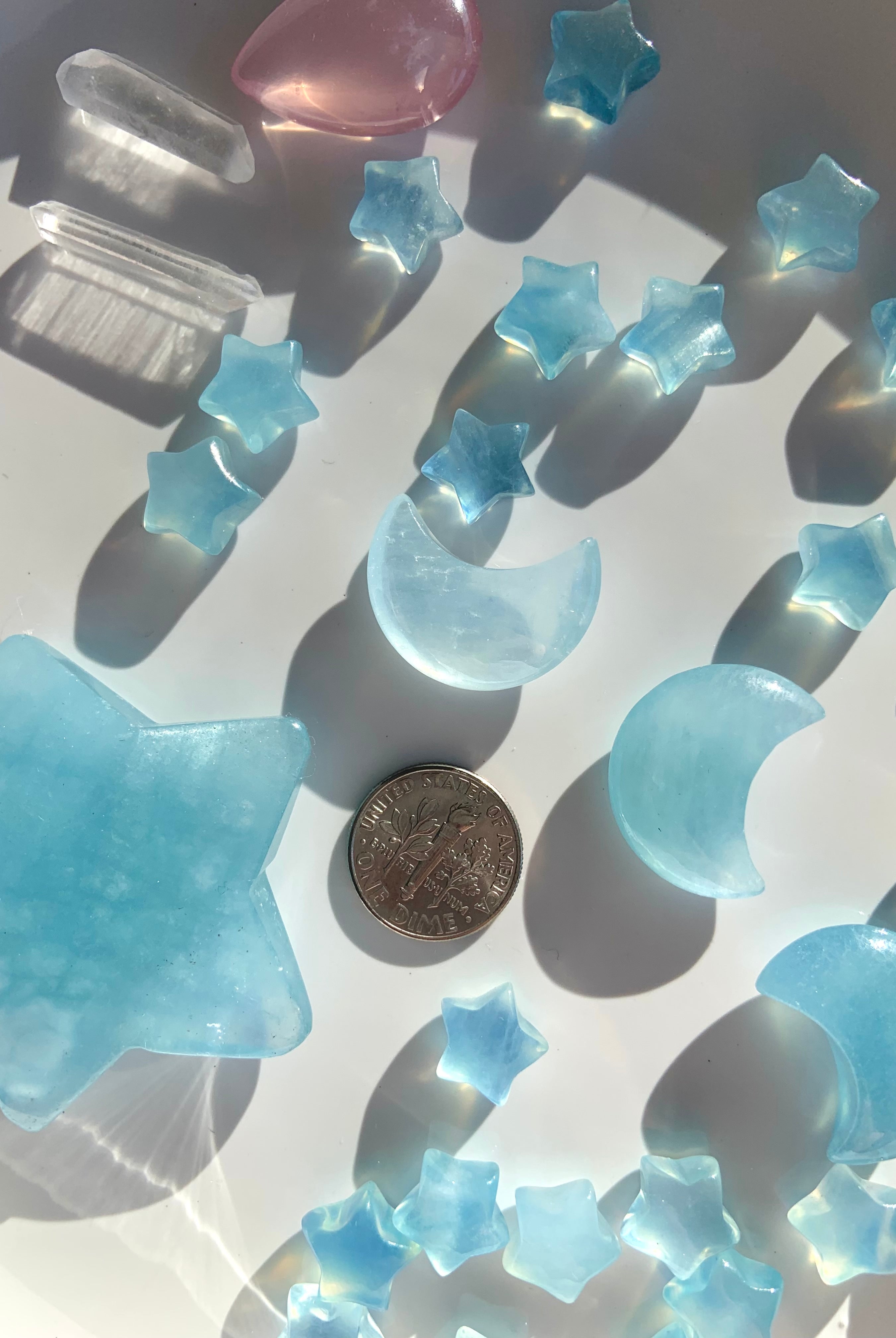 Aquamarine moons and stars next to a dime for scale