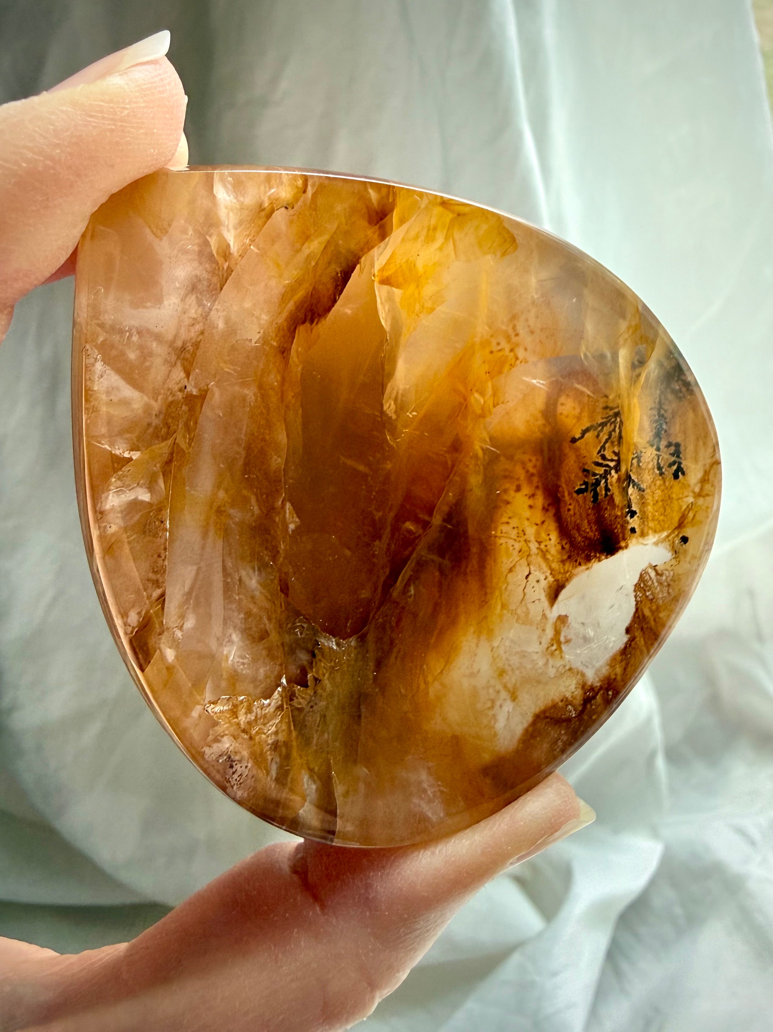 Golden Healer Quartz bowl in hand highlighting translucent golden layers and branch-like dendritic inclusion