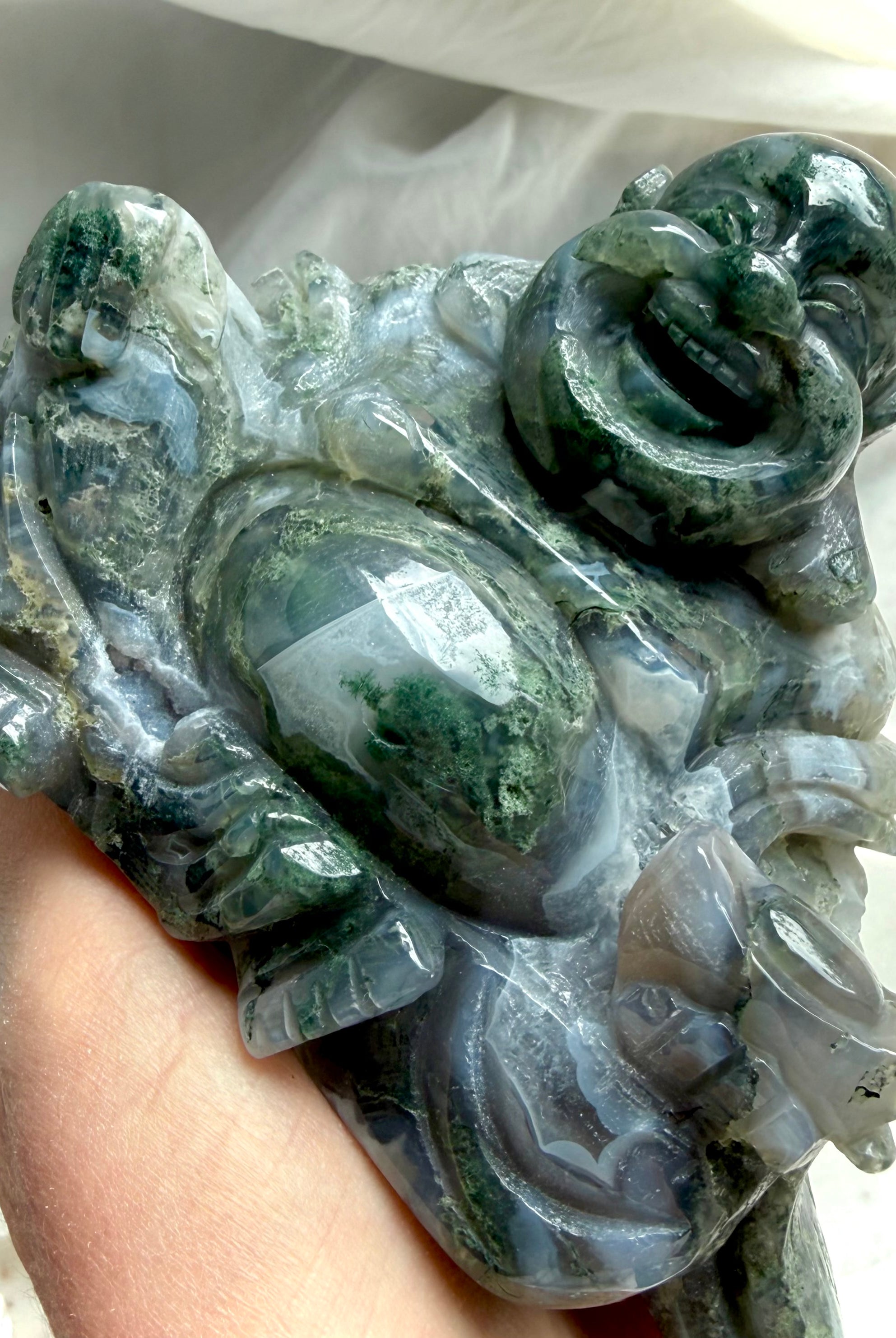Close-up of a Large Moss Agate Laughing Buddha statue showcasing intricate carving, scenic Moss Agate, and glossy finish