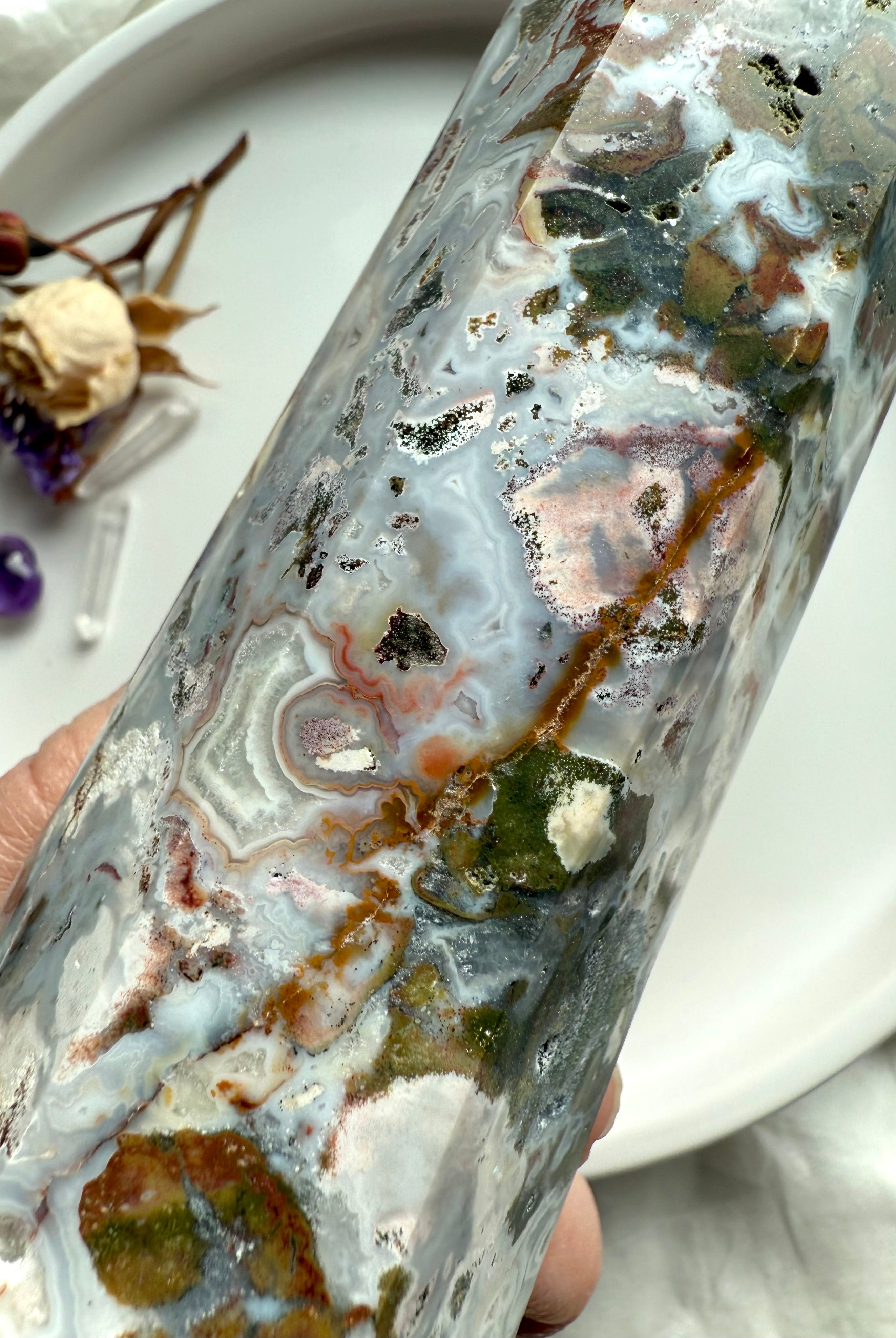 Macro detail of Cosmic Ocean Jasper crystal point with layered ocean-like patterns, mineral inclusions, and sparkling druzy texture