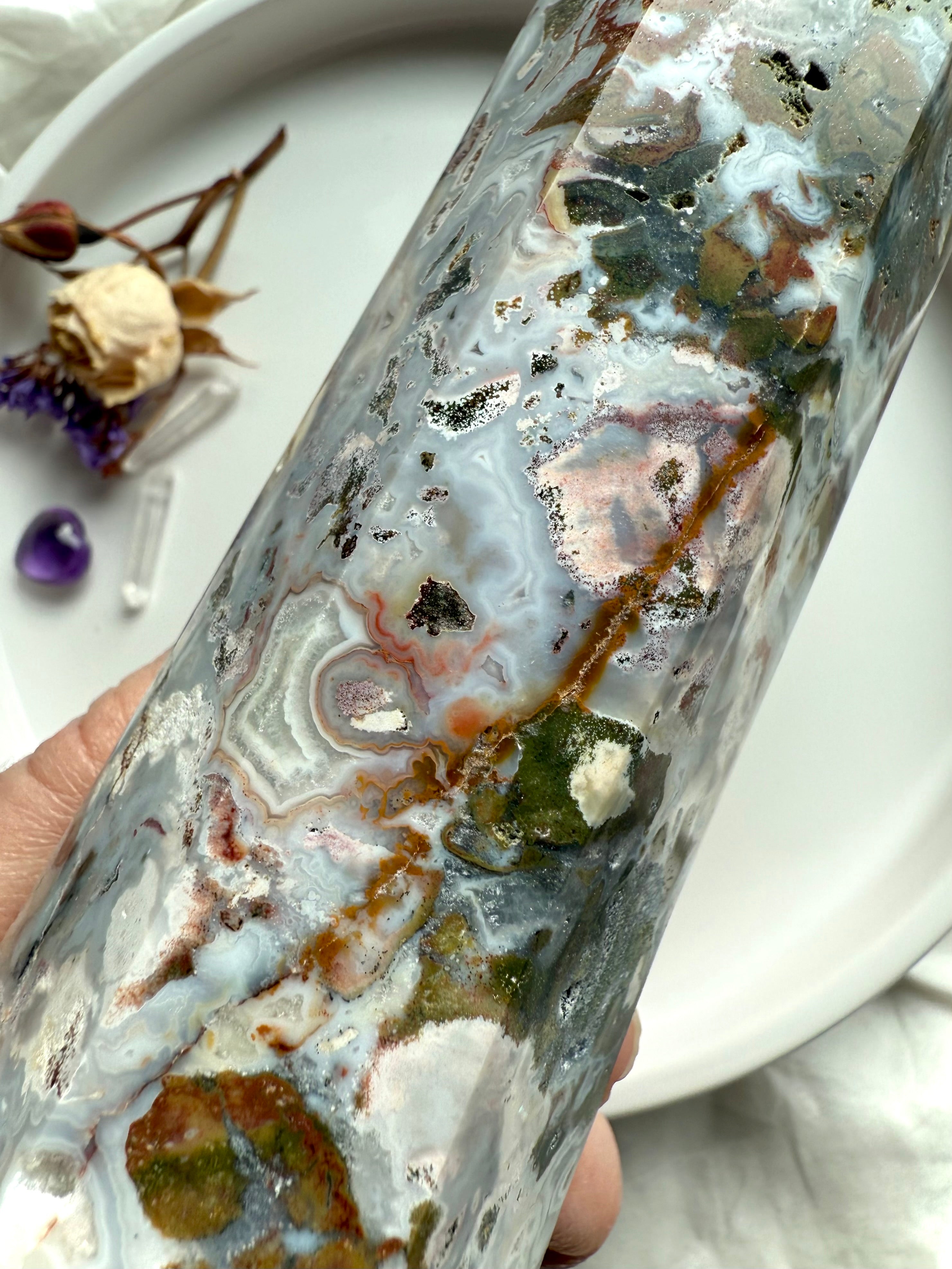 Macro detail of Cosmic Ocean Jasper crystal point with layered ocean-like patterns, mineral inclusions, and sparkling druzy texture