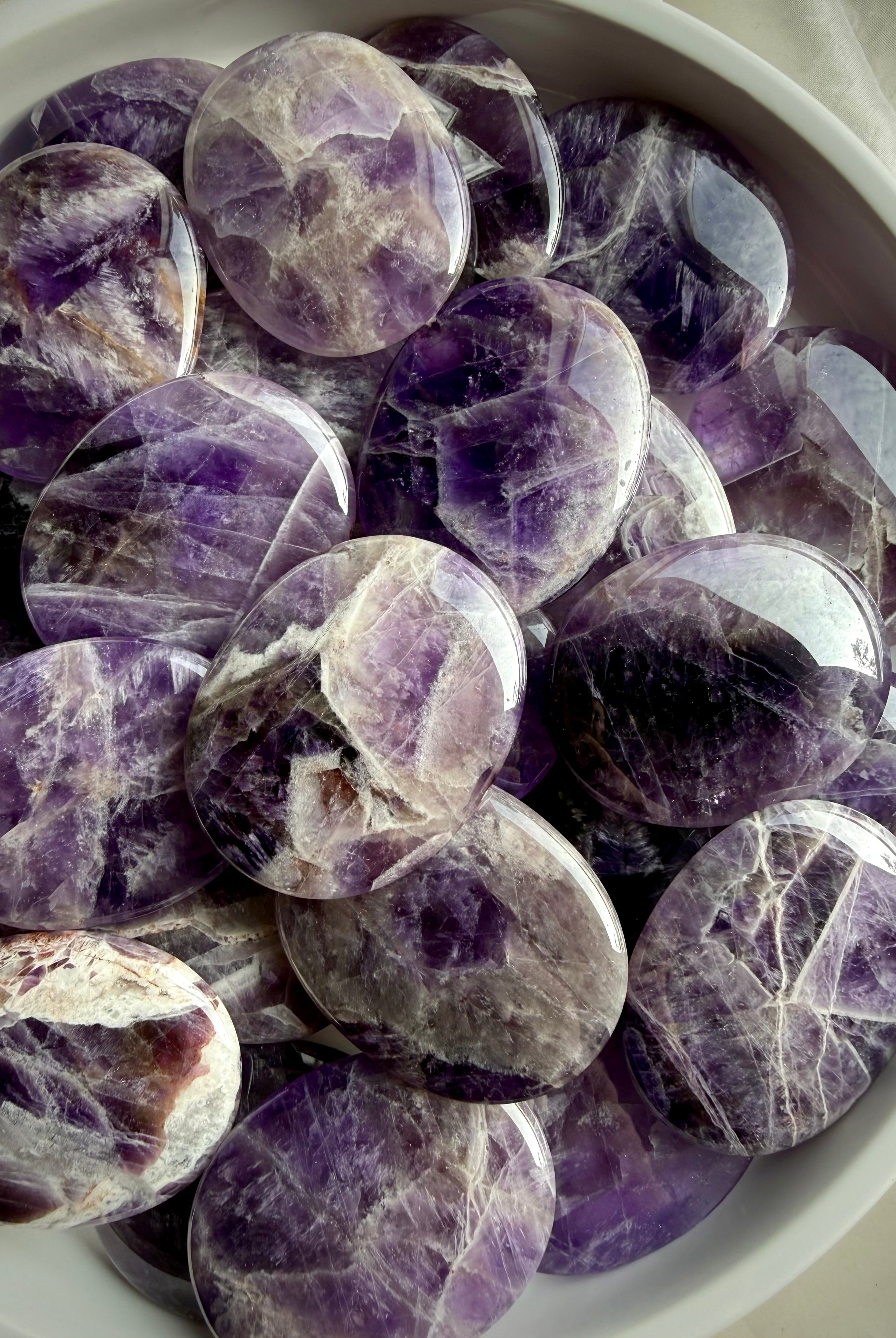 Dream amethyst flat palm stones showing natural variation in purple, lavender, white, and smoky banding, polished pocket crystals for calm and restful sleep