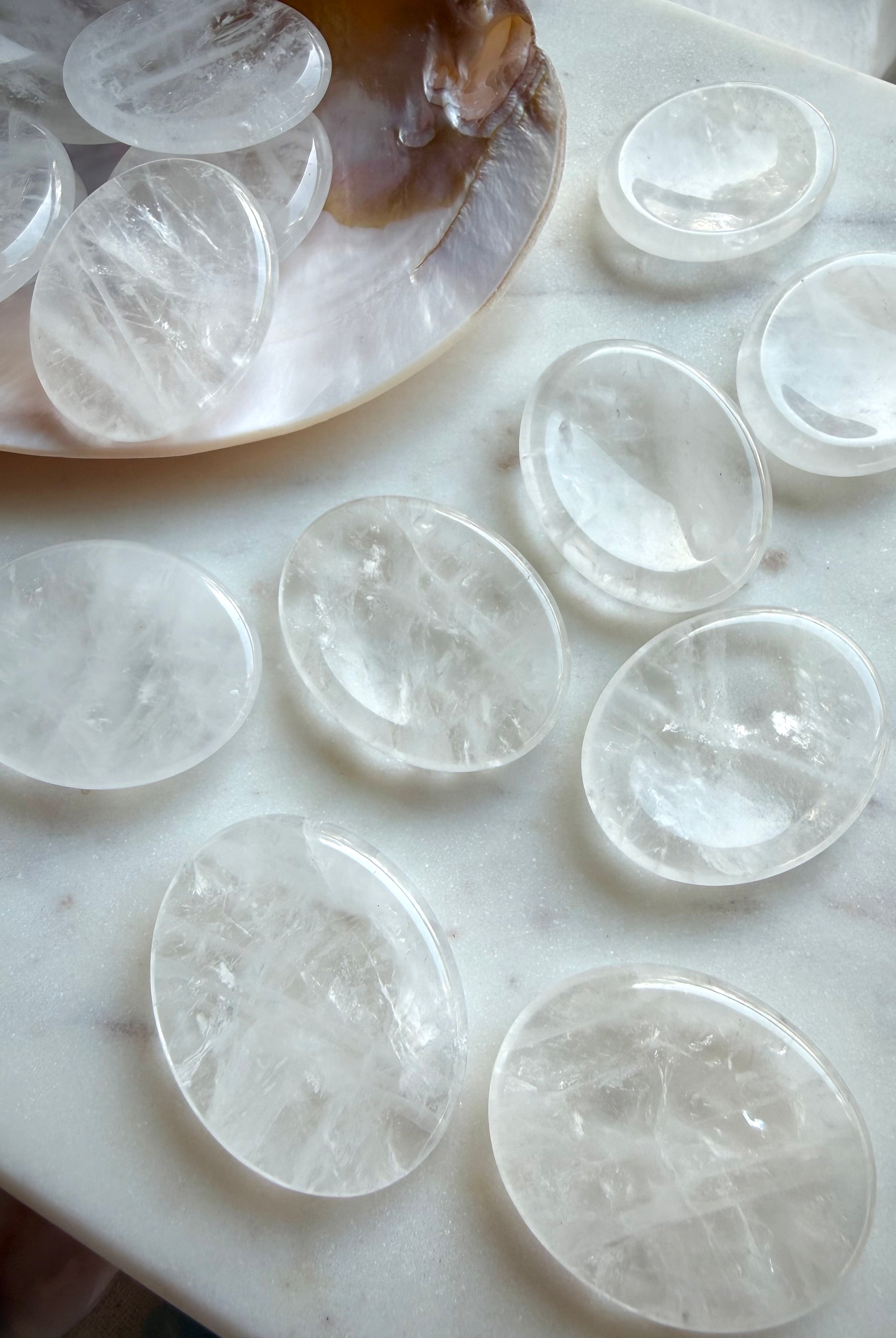 clear quartz worry stones collection on marble surface for energy amplification & spiritual clarity