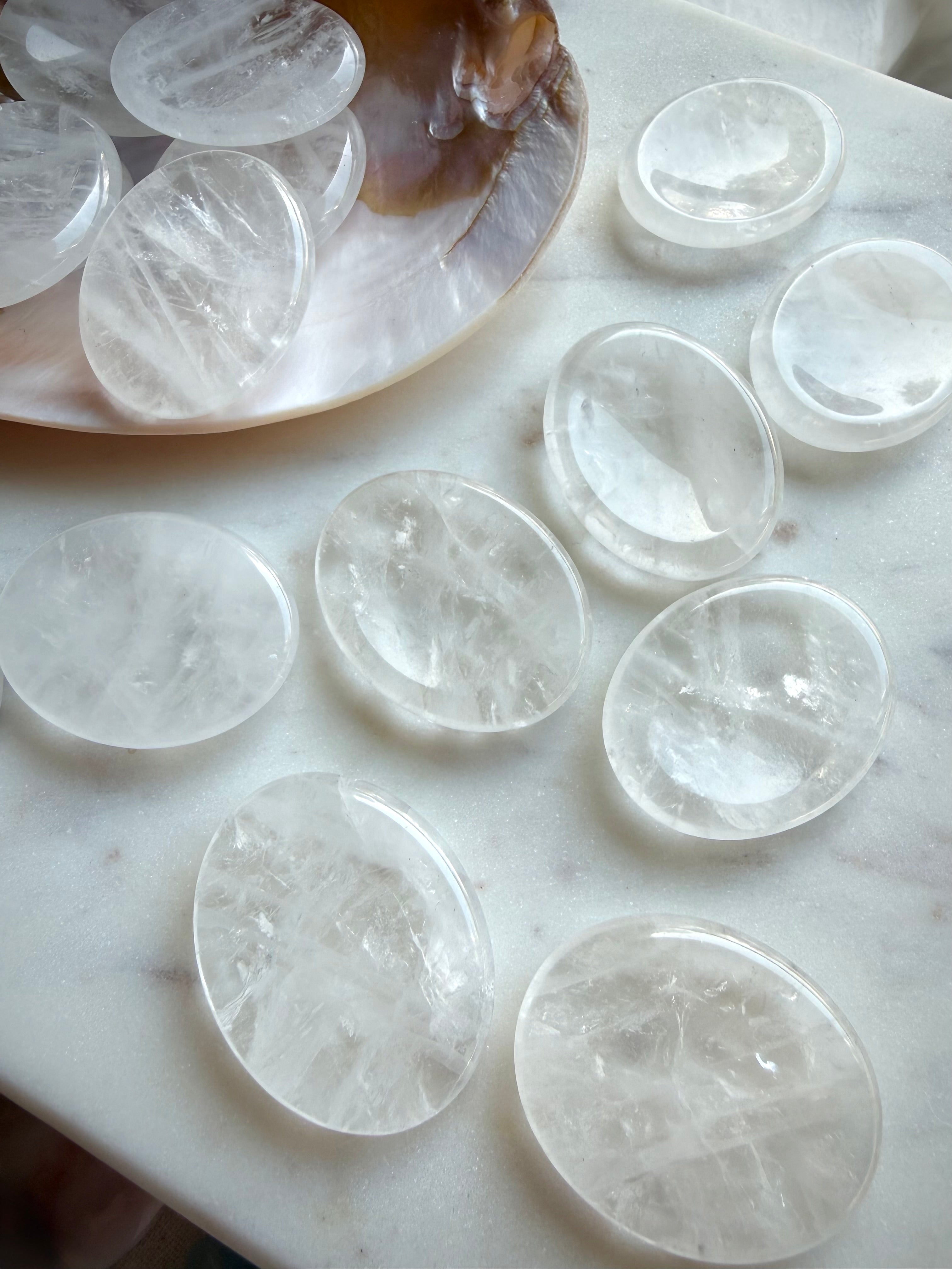clear quartz worry stones collection on marble surface for energy amplification & spiritual clarity