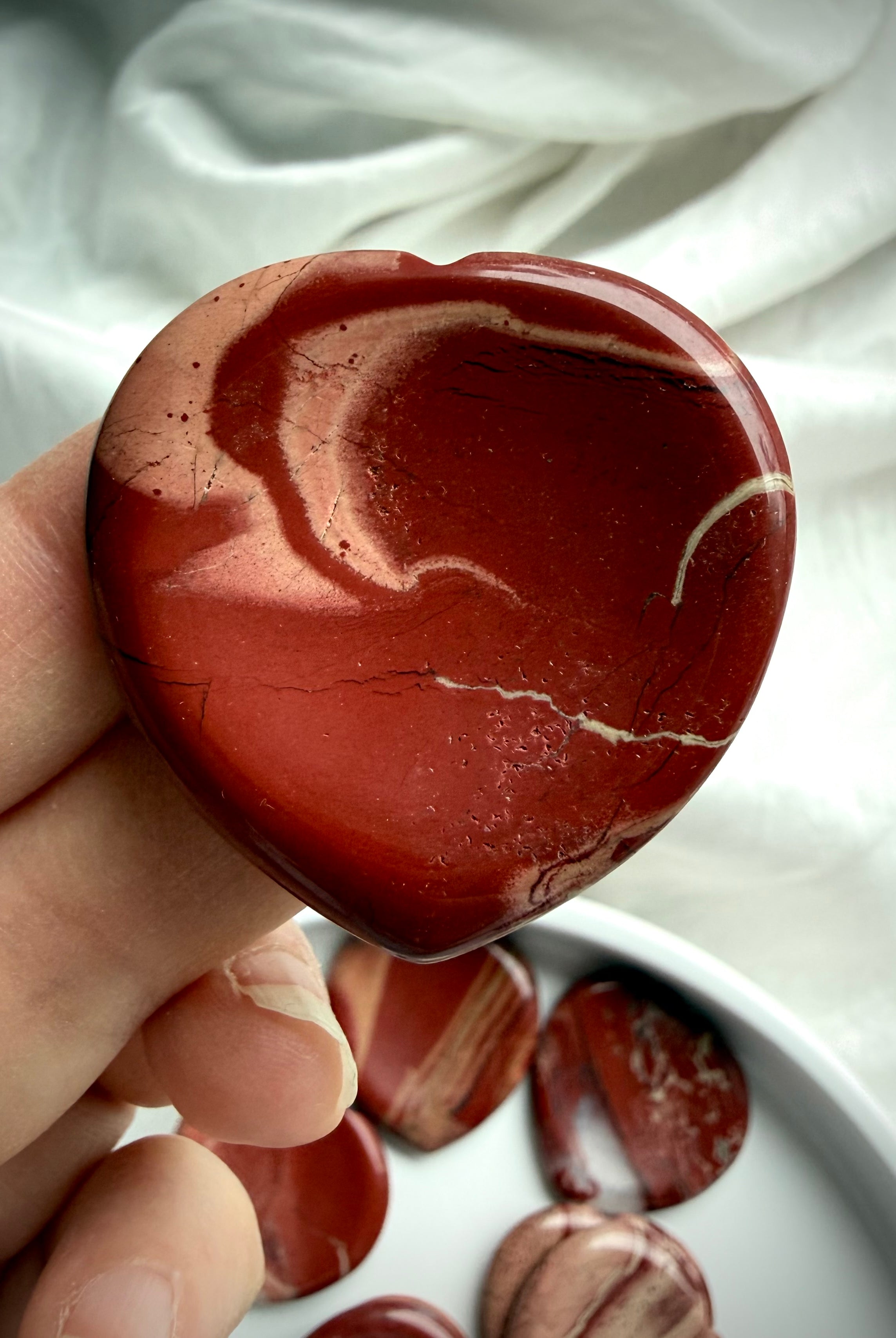 red jasper heart worry stone held in hand – polished grounding crystal for meditation and Root Chakra support