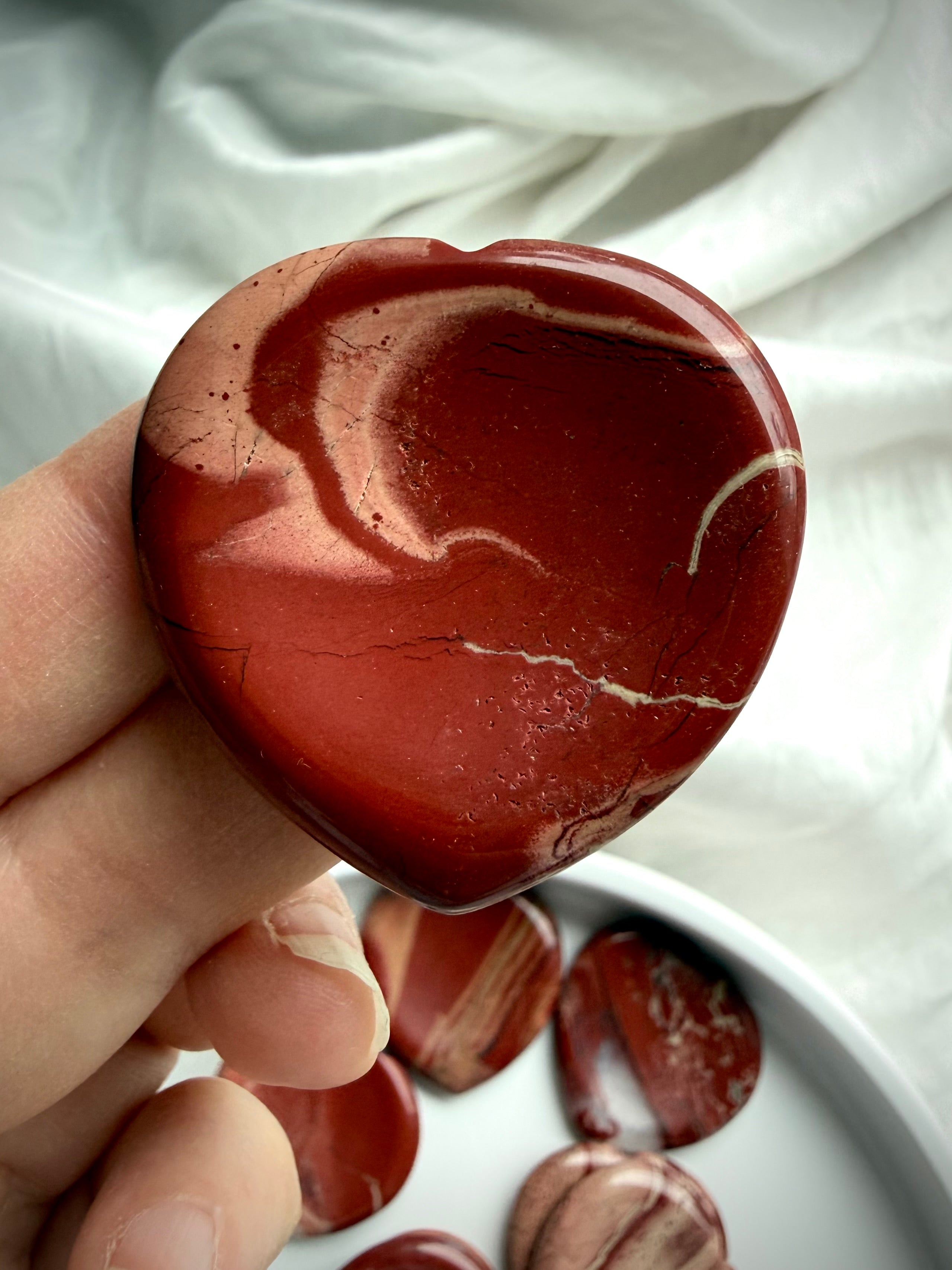 red jasper heart worry stone held in hand – polished grounding crystal for meditation and Root Chakra support
