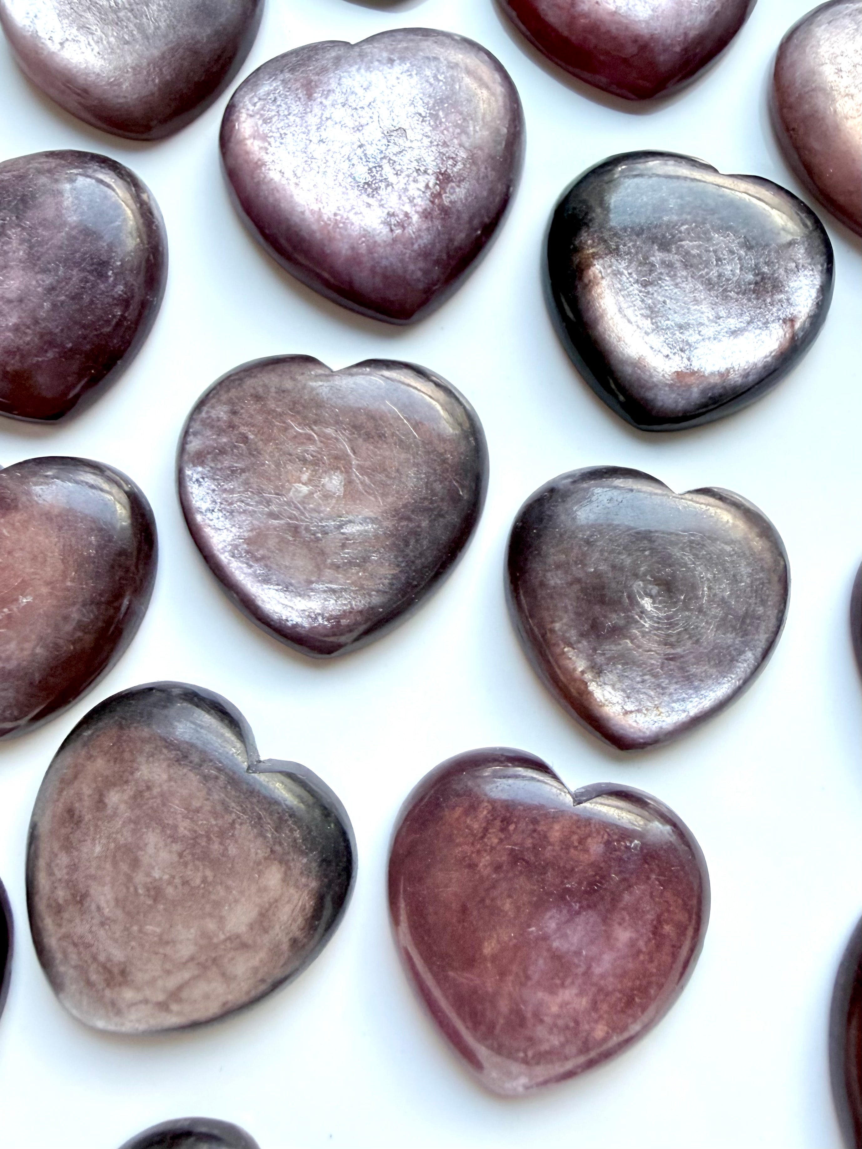 Close-up of lepidolite heart carvings highlighting natural mica layers and reflective sheen