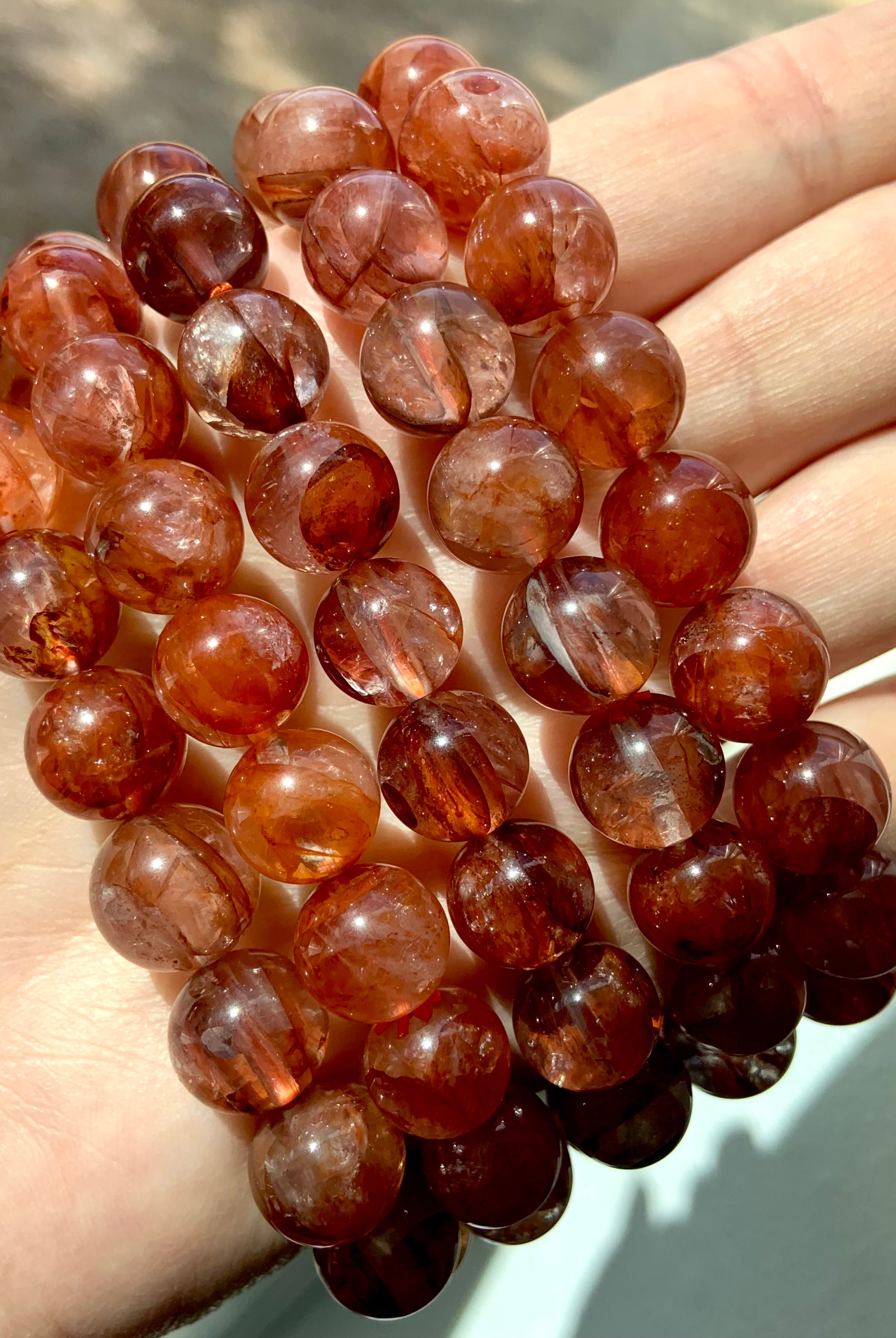 Close-up side view of several high-quality Fire Quartz bracelets, highlighting natural color patterns and glossy polished beads