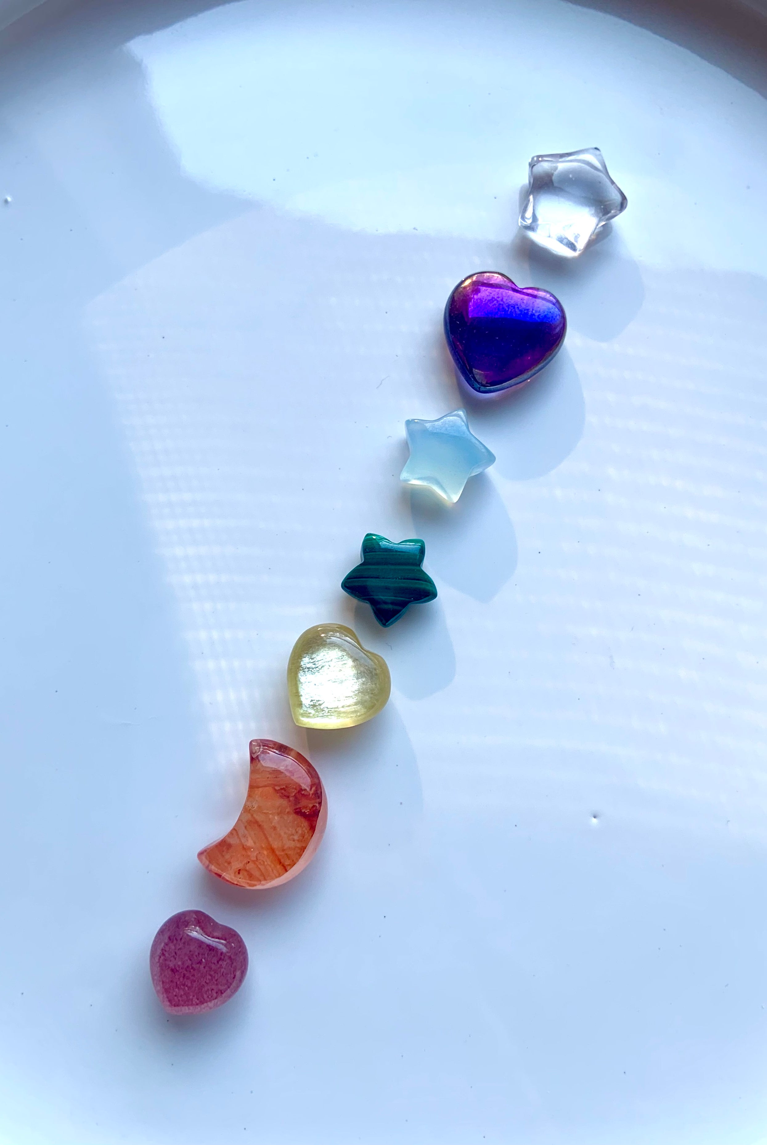 Vertical arrangement of rainbow mini chakra gemstones carved in celestial shapes for each chakra