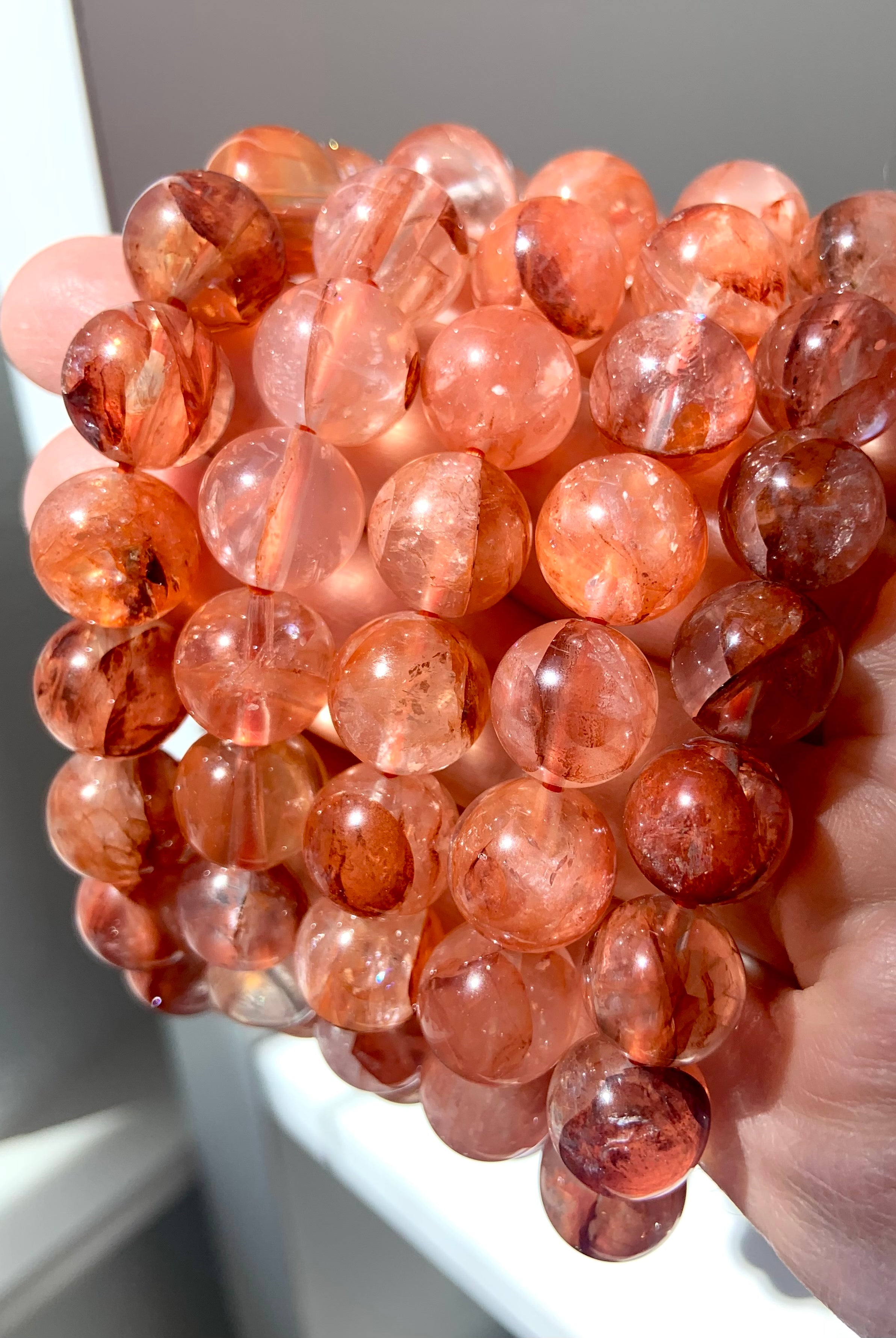 Side view of multiple Fire Quartz crystal bracelets, showcasing bead size, rich color, and natural inclusions
