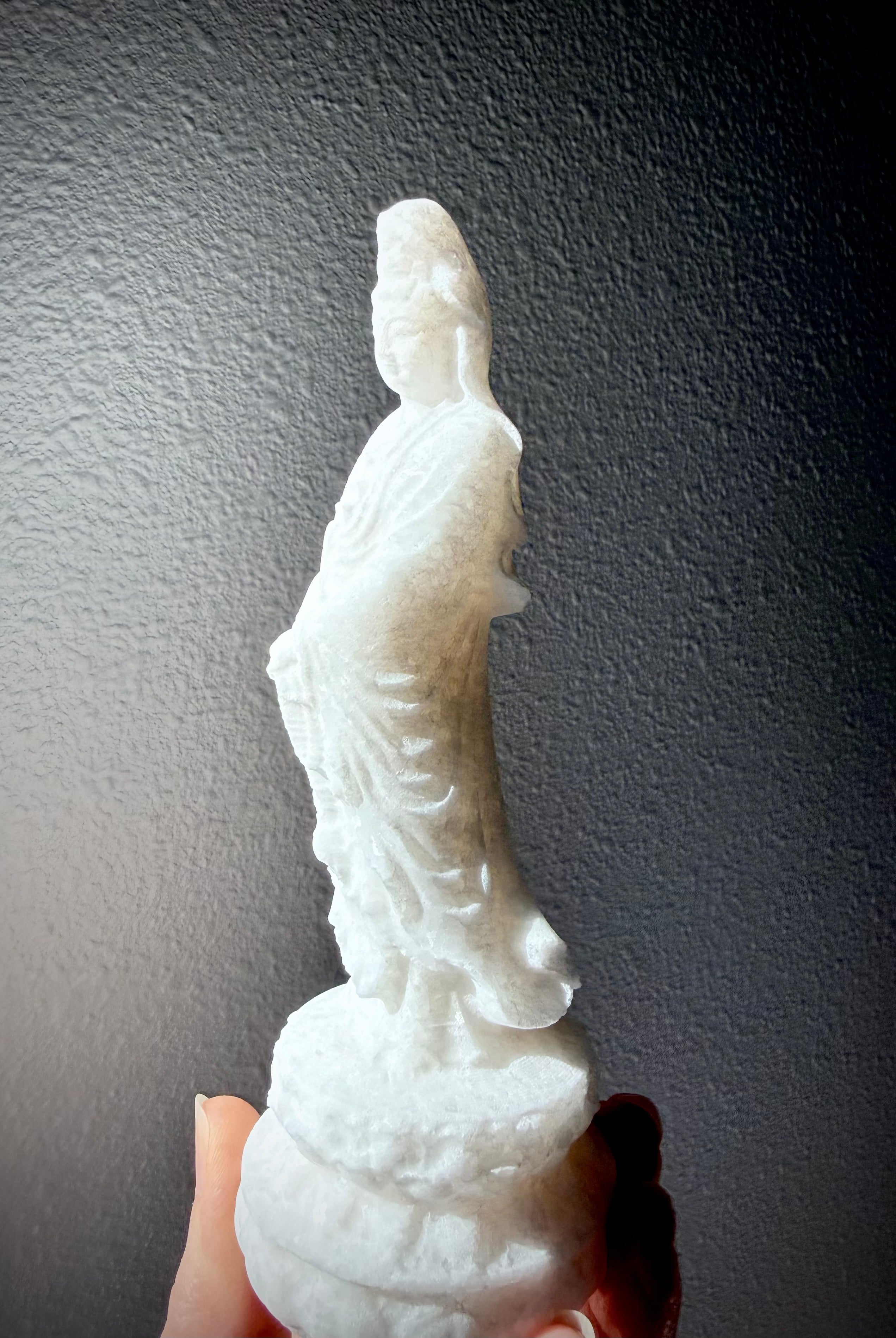 White Jade Quan Yin statue held in hand showing soft translucency and natural crystalline sparkle