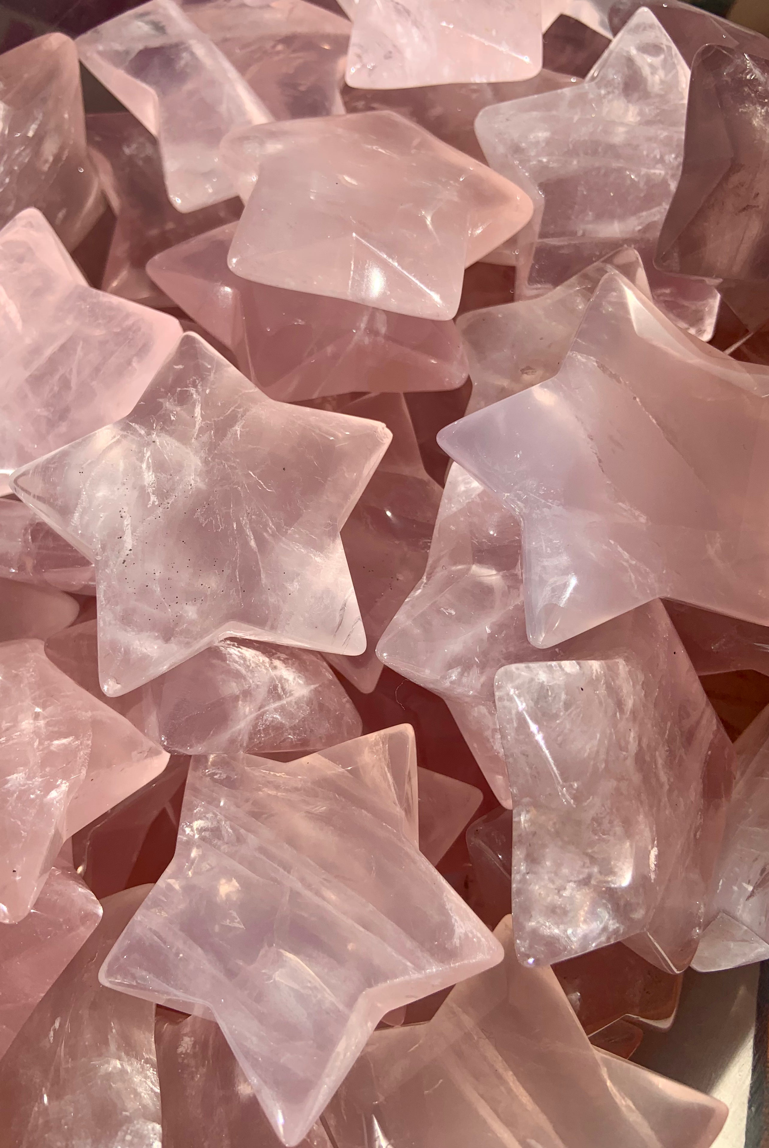 pile of large Mozambique rose quartz star carvings showing natural pink hue and polished crystal texture