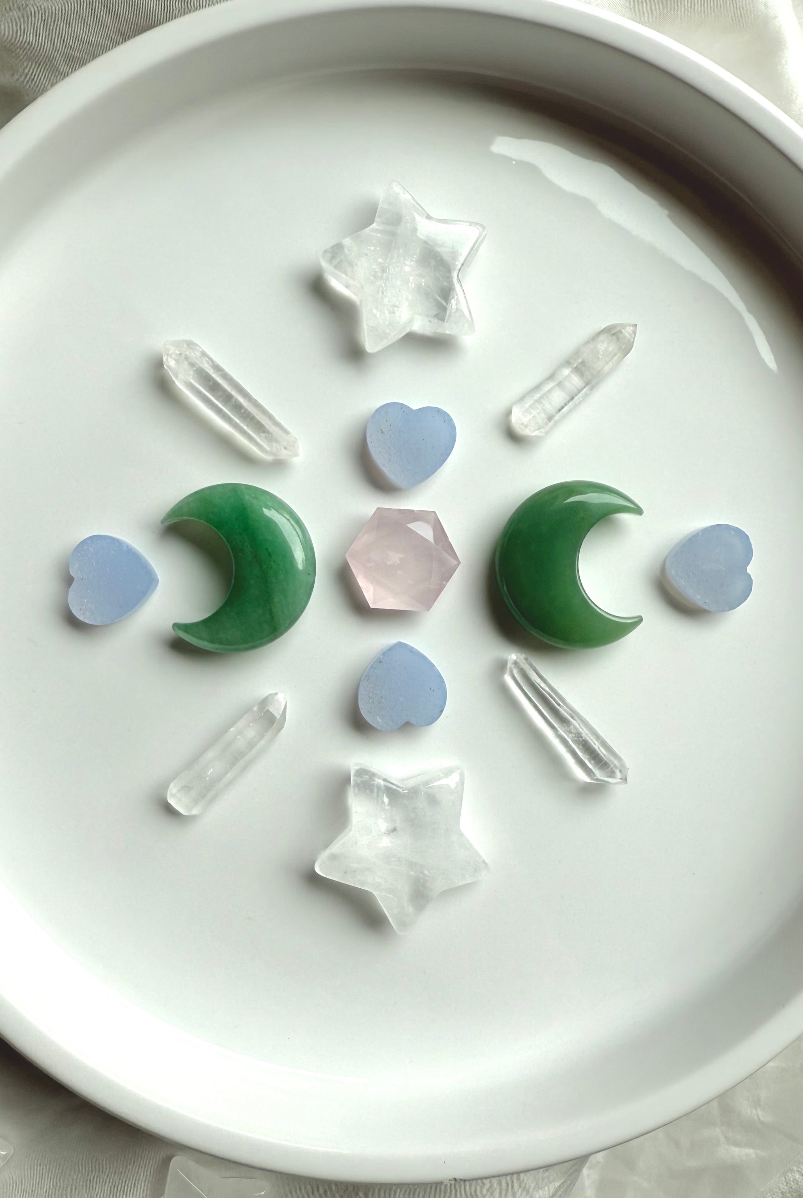 Crystal grid with Clear Quartz stars, Green Aventurine moons, Blue Chalcedony hearts, quartz points, and Rose Quartz hexagon in center, sacred geometry layout for healing